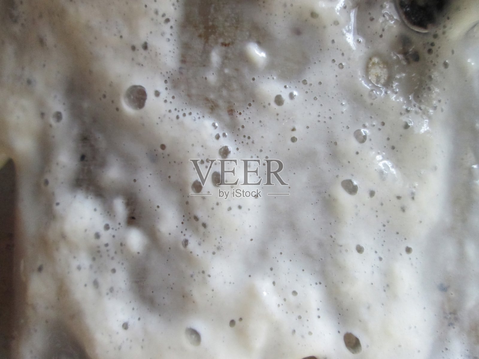 这张特写展示了一个碗里冒着泡泡的泡沫混合物，展示了厨房里正在进行的烹饪实验所产生的质地和泡沫。照片摄影图片