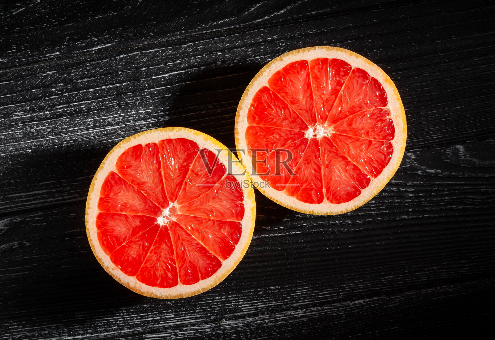 切好的葡萄柚放在黑木头上照片摄影图片