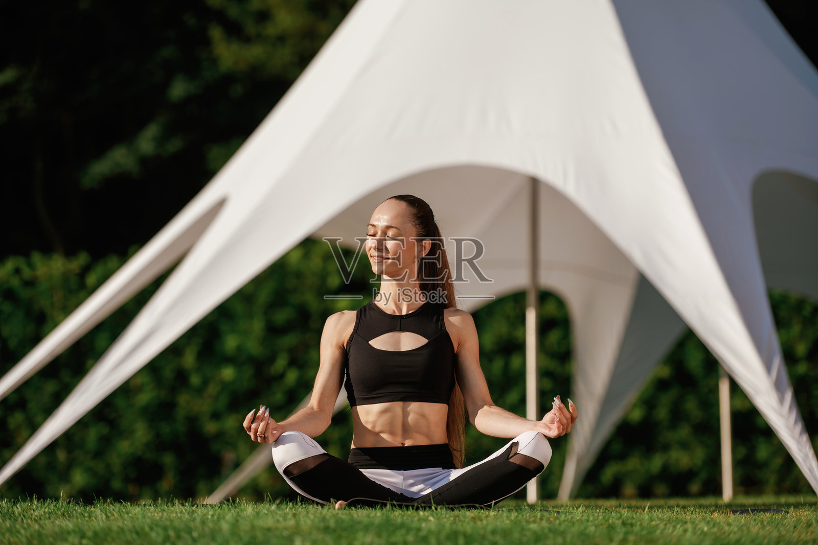 后面是白色帐篷。健身女人是户外，美丽的度假场所照片摄影图片