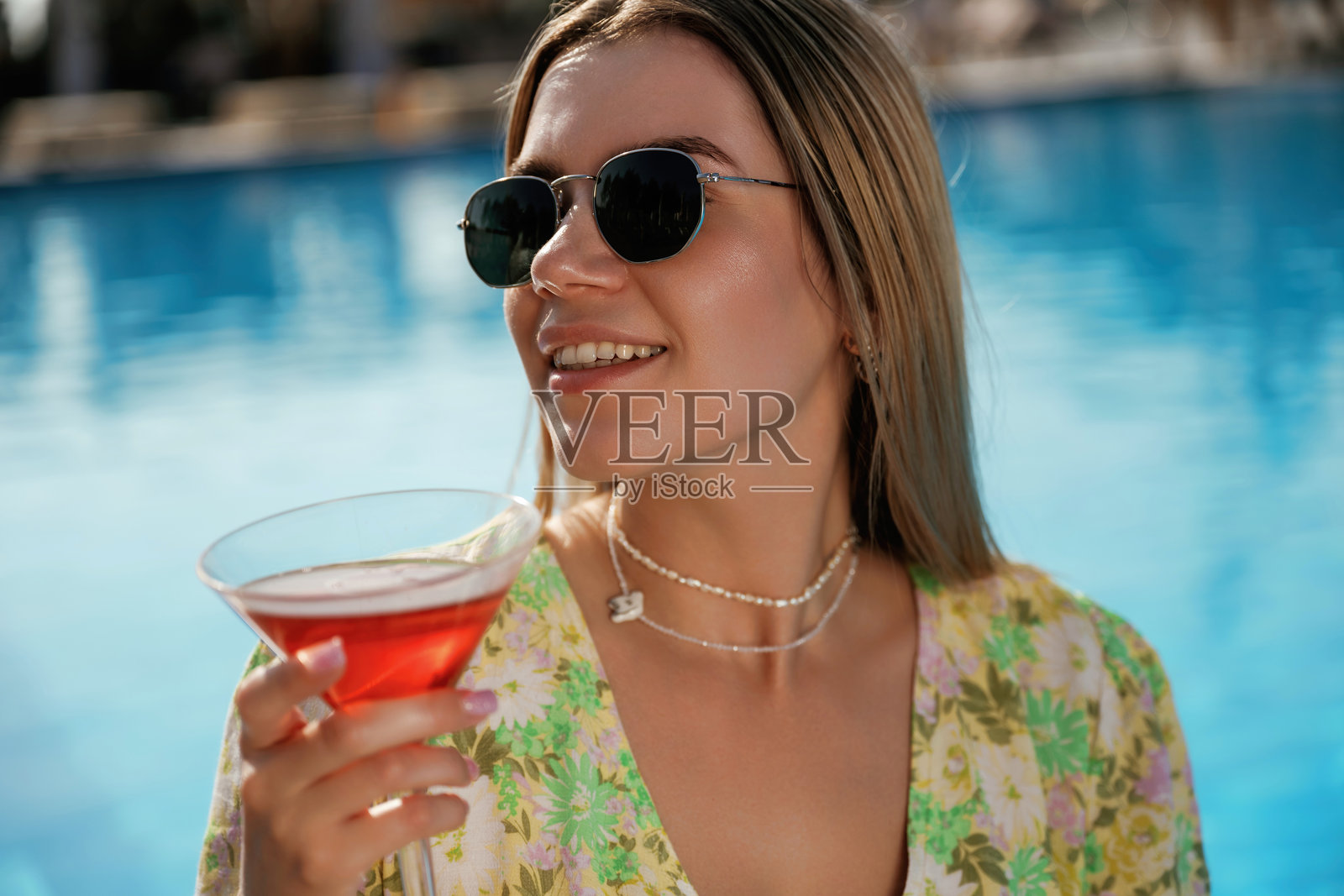 戴着墨镜，喝着鸡尾酒。美丽的年轻女子正在度假照片摄影图片