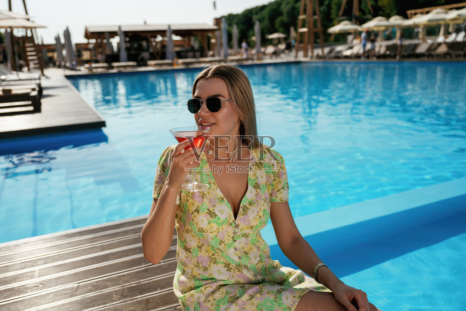 靠在泳池边。美丽的年轻女子正在度假照片摄影图片