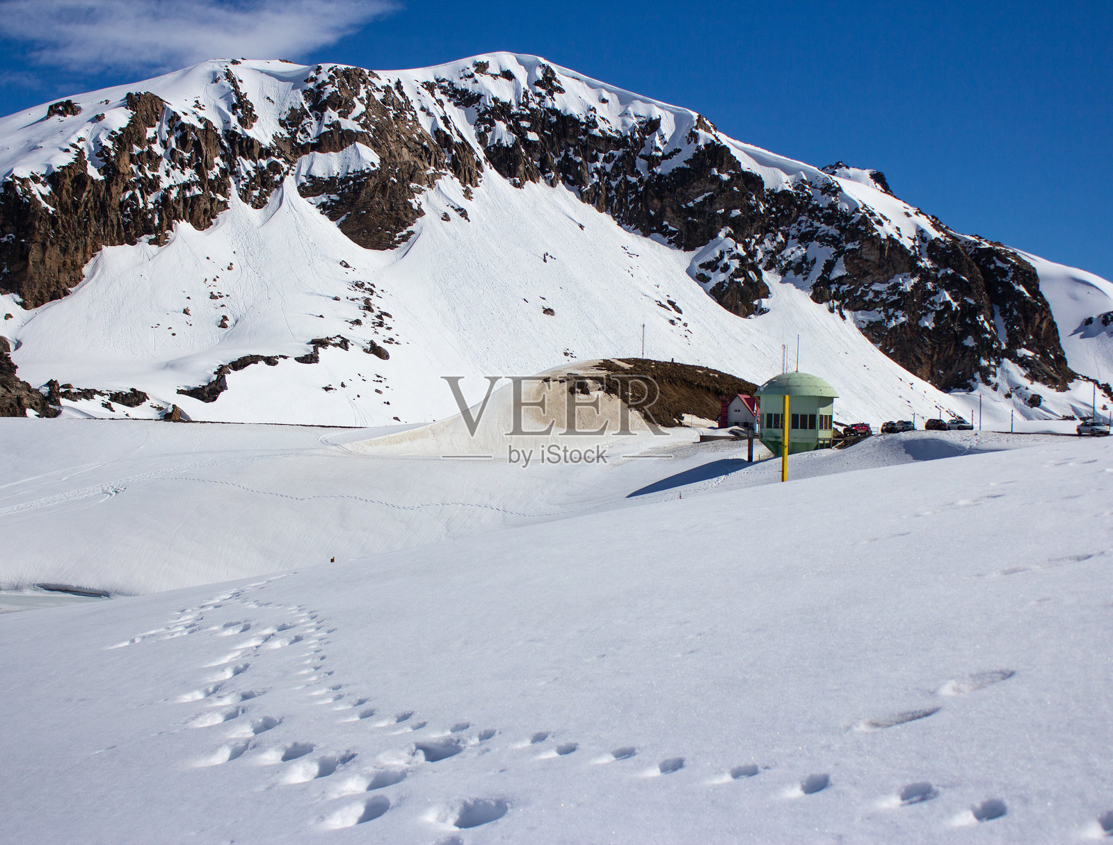在南美的雪山上，你可以看到人们在雪中的脚印和背景中的一座山照片摄影图片