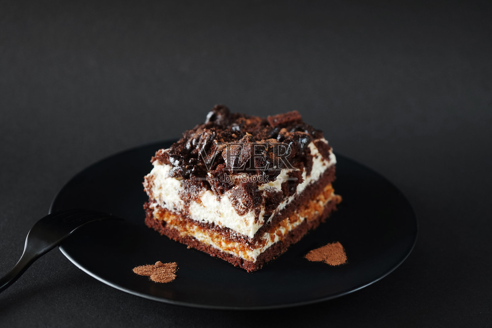 咖啡味的巧克力蛋糕放在叉子旁边的黑色盘子里照片摄影图片