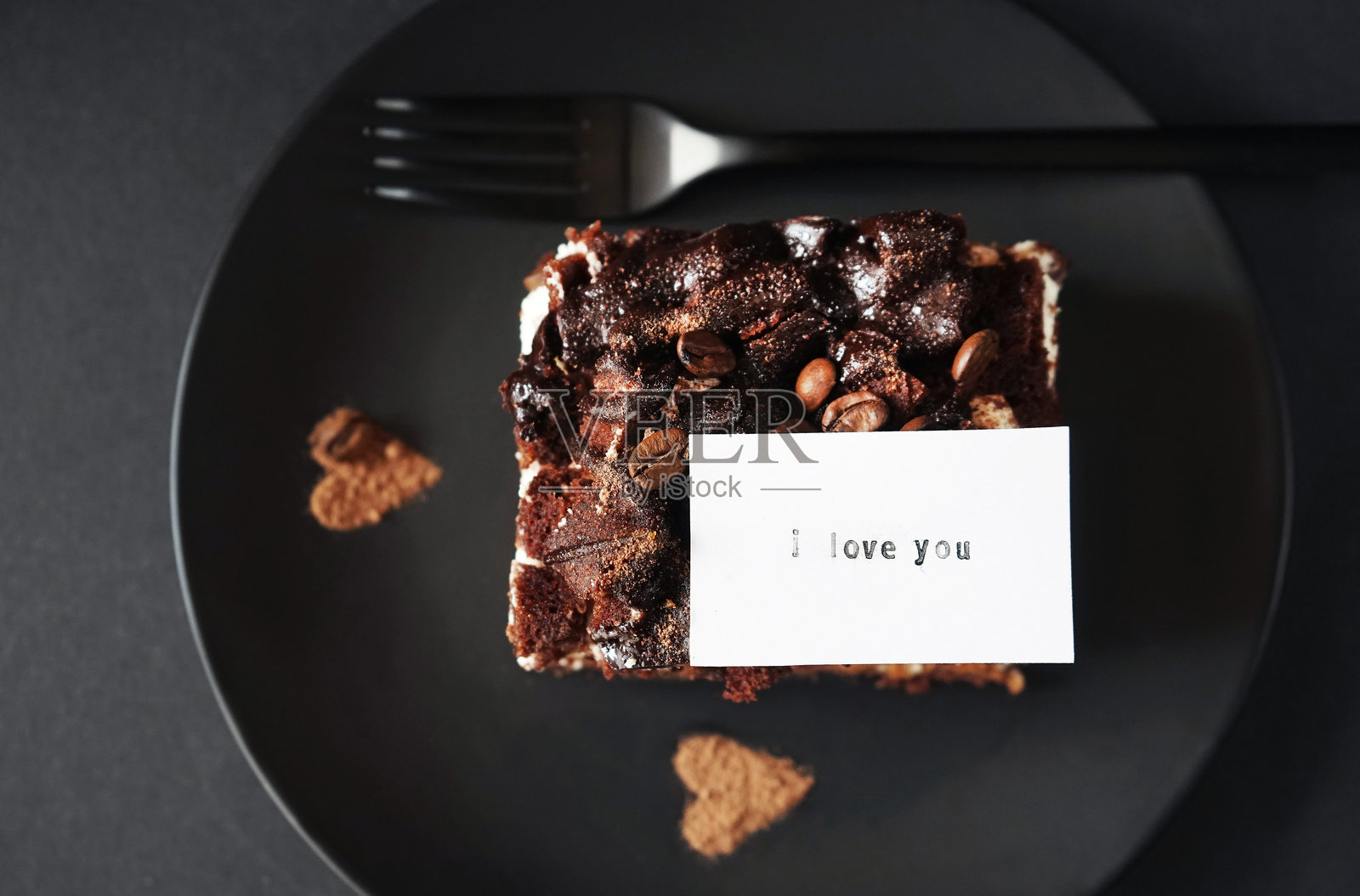 咖啡口味的巧克力蛋糕，在叉子旁边的黑色盘子上有一张题字卡片照片摄影图片