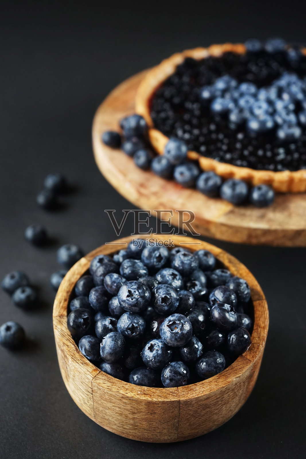 木碗里装着新鲜的蓝莓，旁边是木摊上的蓝莓馅饼照片摄影图片