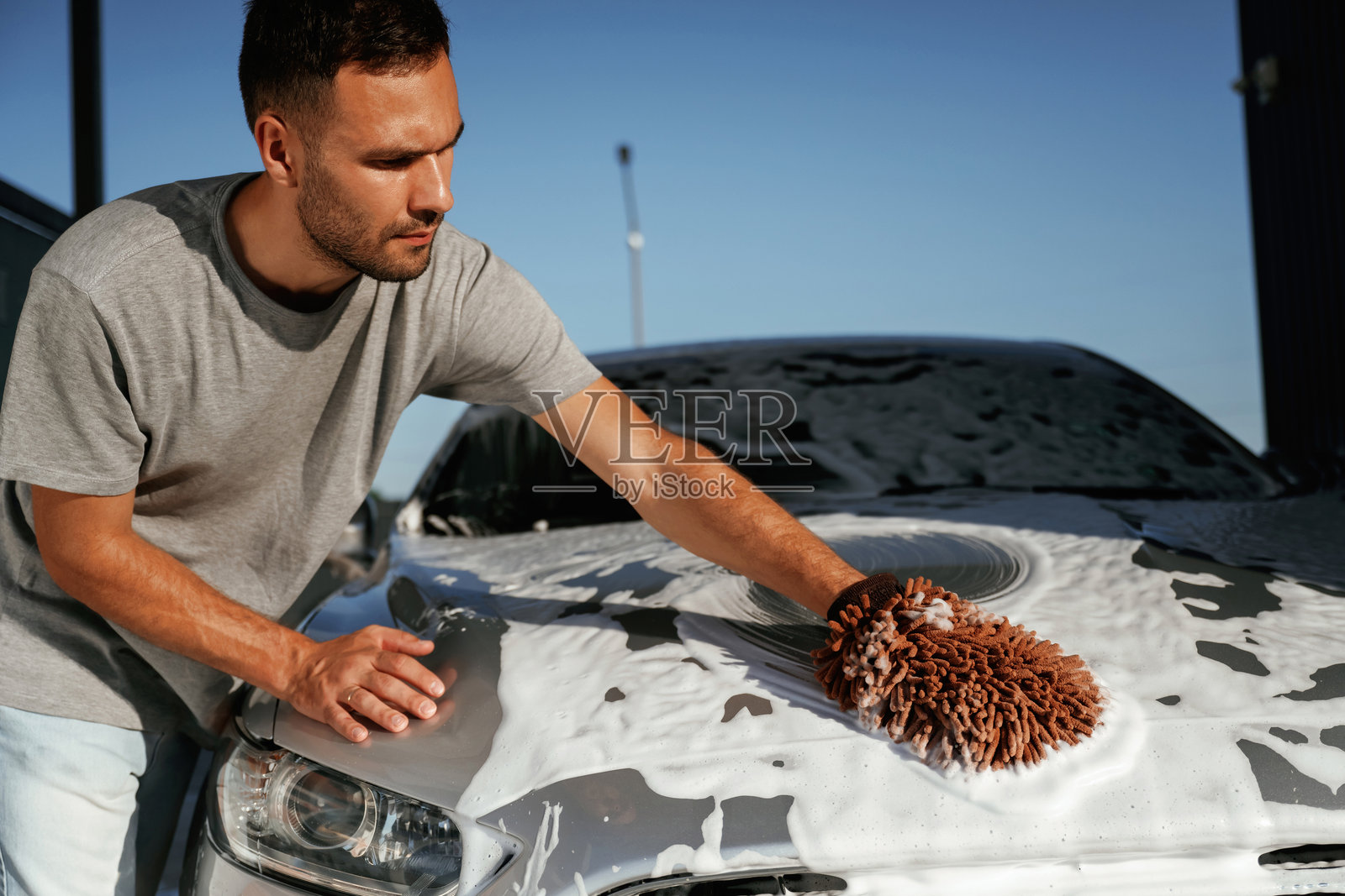 白色清洗剂，清洗汽车。一个男人和他的车在外面照片摄影图片