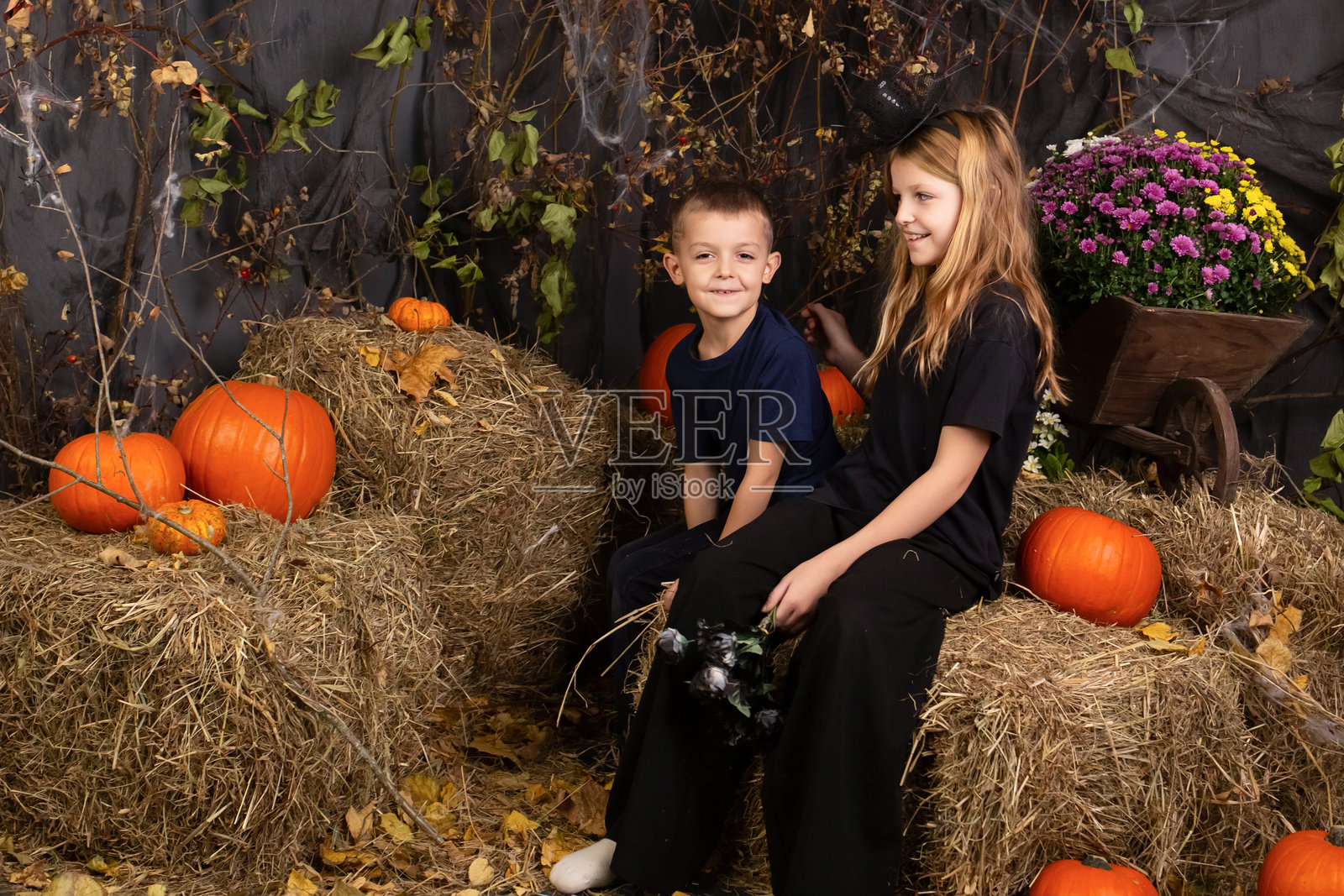 快乐的兄弟姐妹万圣节。在室内穿着狂欢节服装的有趣的孩子们。兴高采烈的孩子们在玩南瓜照片摄影图片