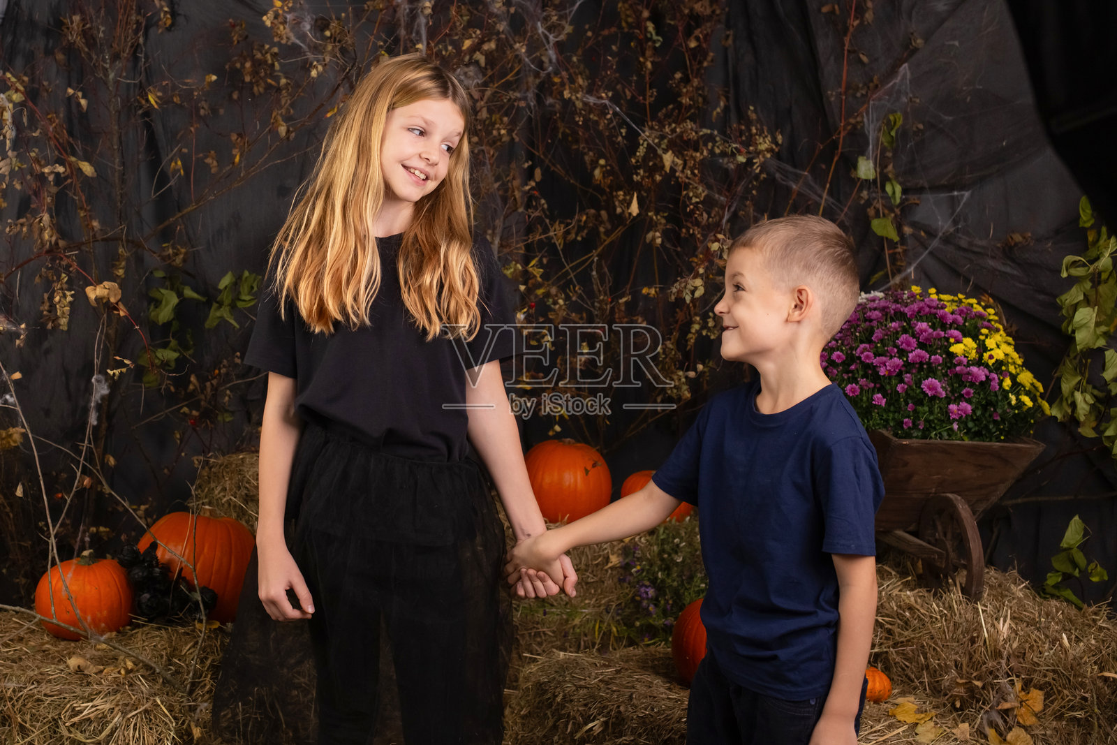 快乐，有趣的孩子们的特写肖像，他们的头上拿着南瓜。孩子们在为万圣节做准备照片摄影图片