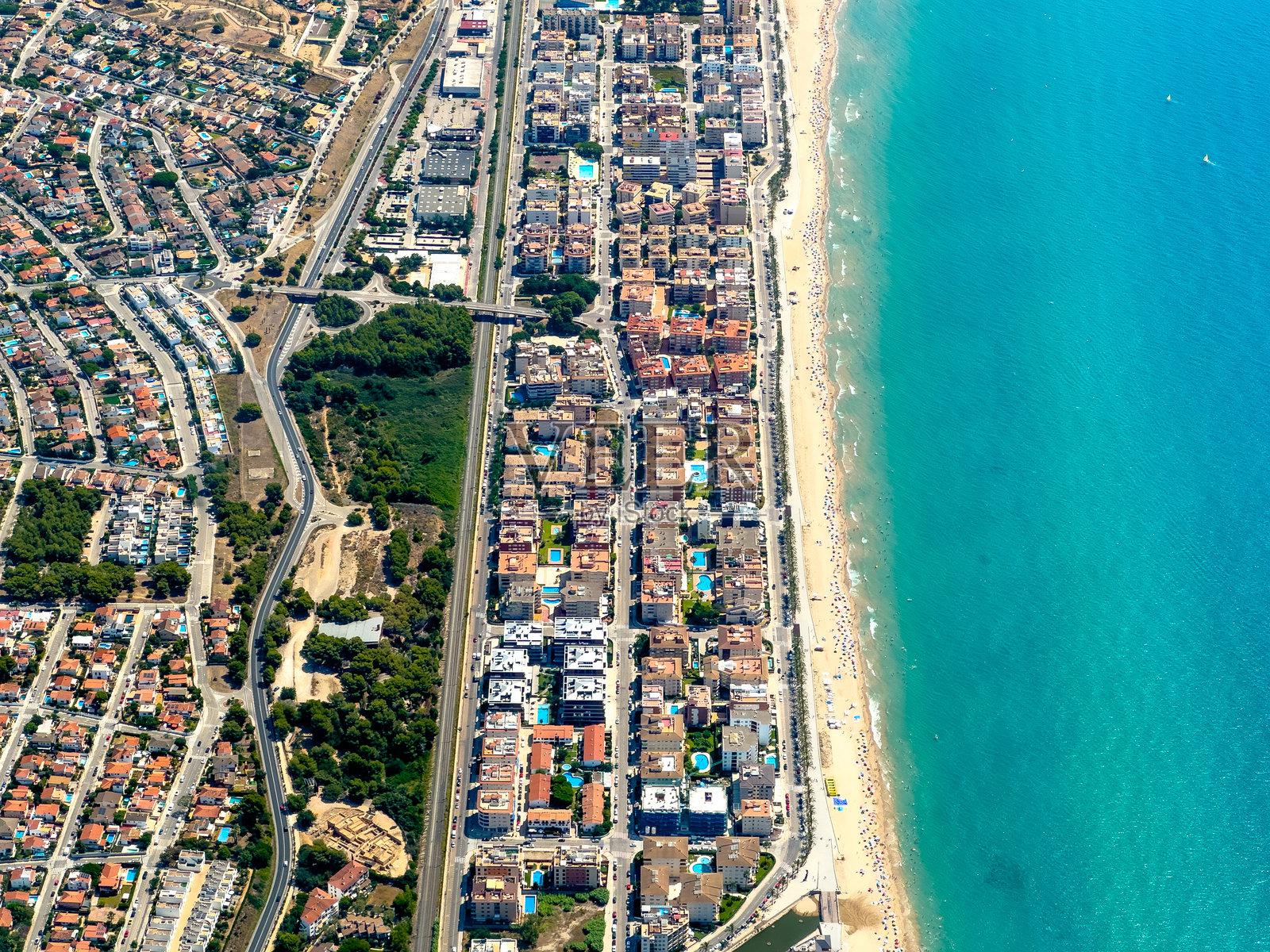 从空中俯瞰巴塞罗那南部的海岸线，海滩，林荫大道和公寓建筑沿着海岸和海滩在夏天的一天照片摄影图片