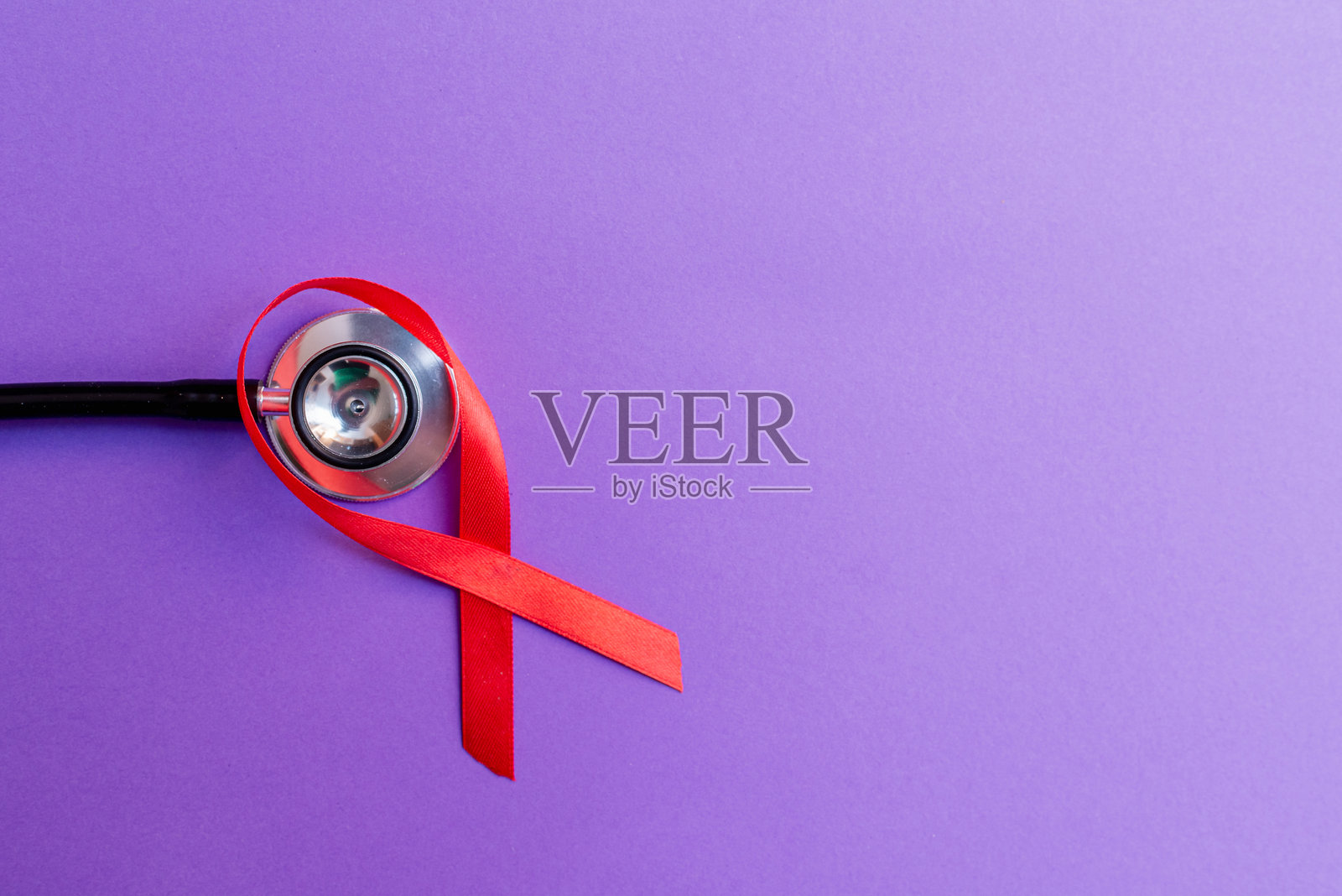 女性乳腺癌的概念。红丝带，紫色背景上的听诊器。俯视图，复制空间。照片摄影图片