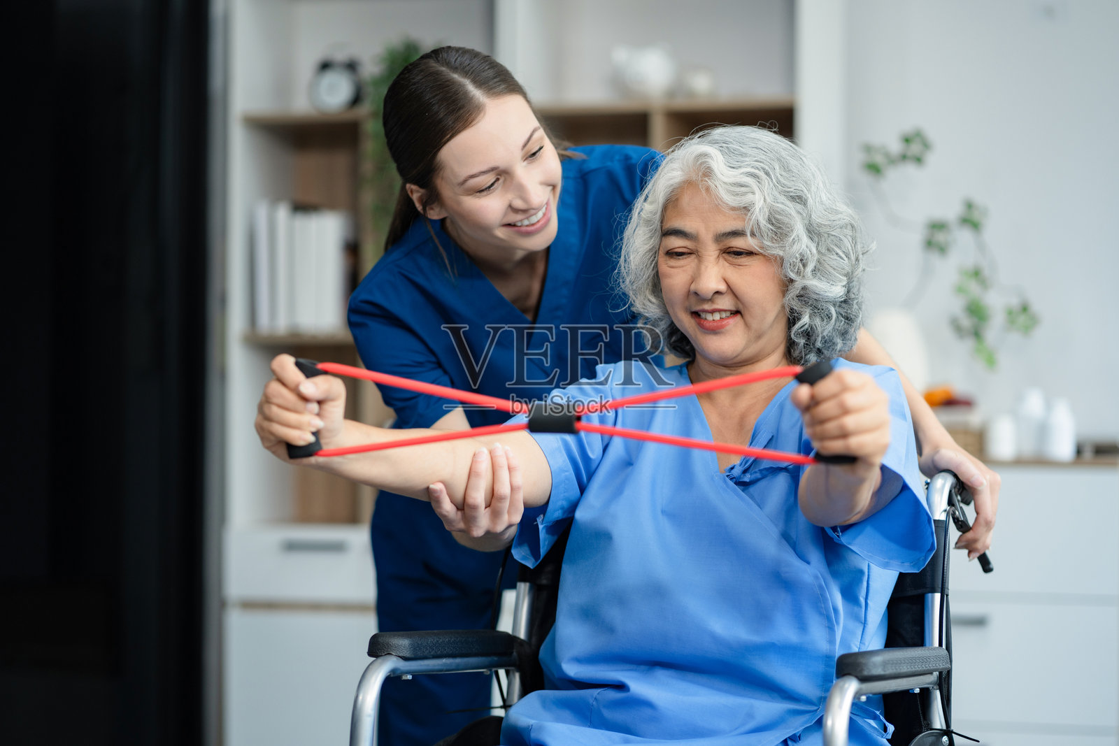 老年妇女在诊所与理疗师一起做运动。在康复训练期间，私人教练的帮助。照片摄影图片