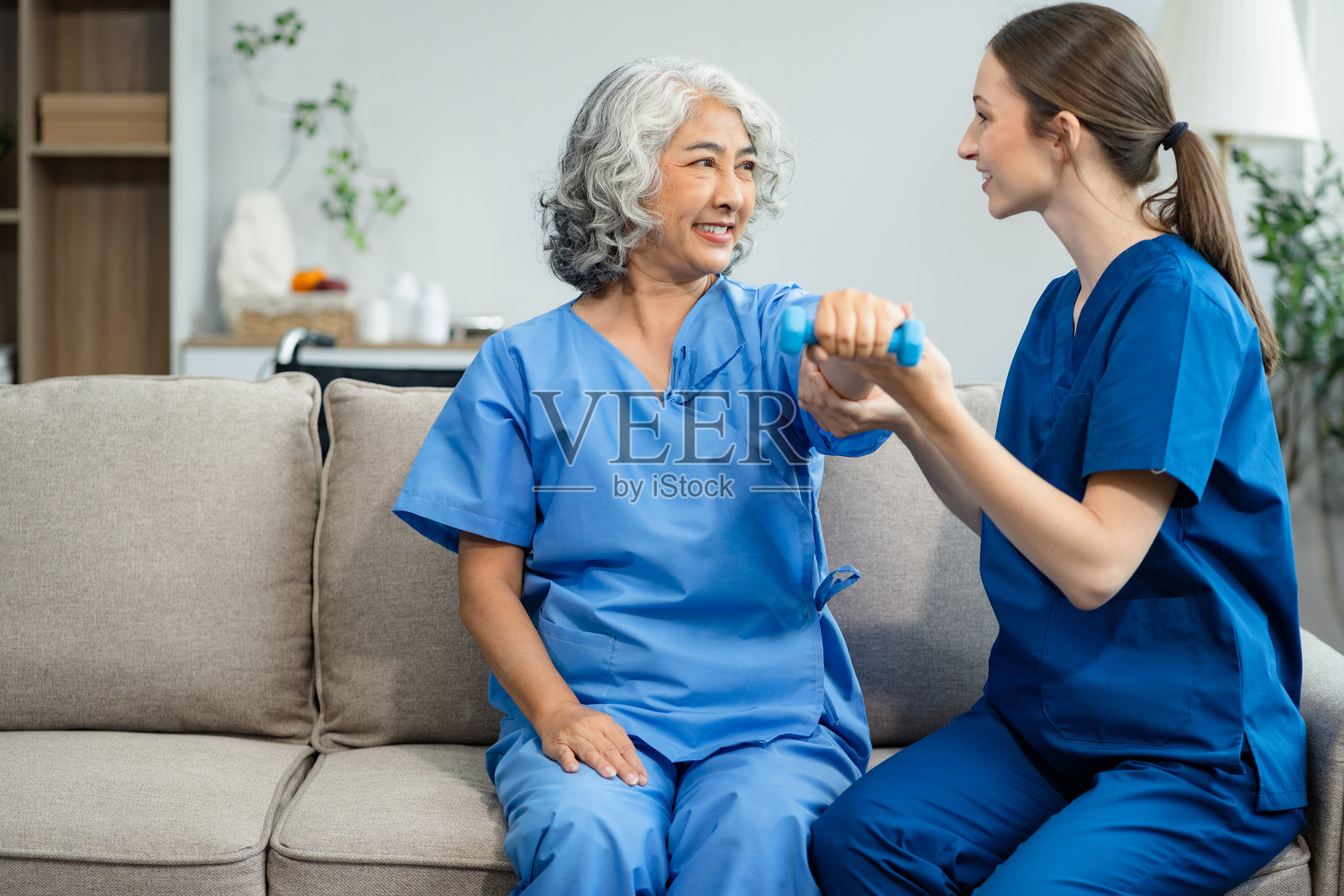老年妇女在诊所与理疗师一起做运动。在康复训练期间，私人教练的帮助。照片摄影图片