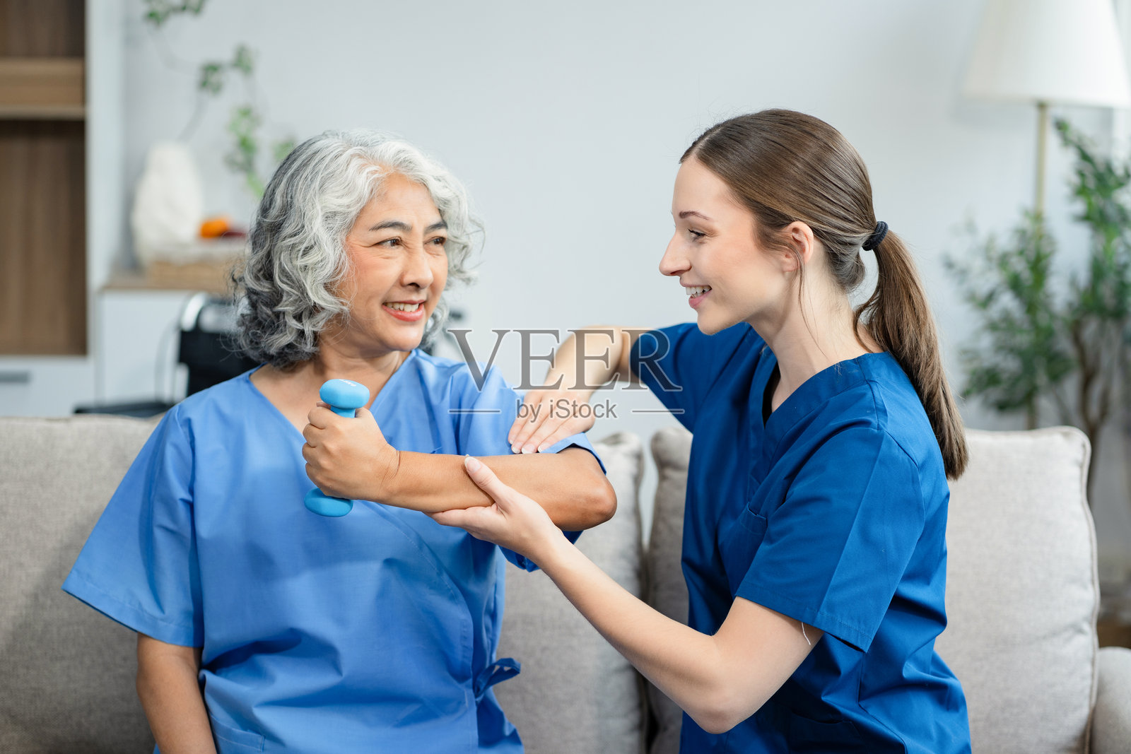 老年妇女在诊所与理疗师一起做运动。在康复训练期间，私人教练的帮助。照片摄影图片