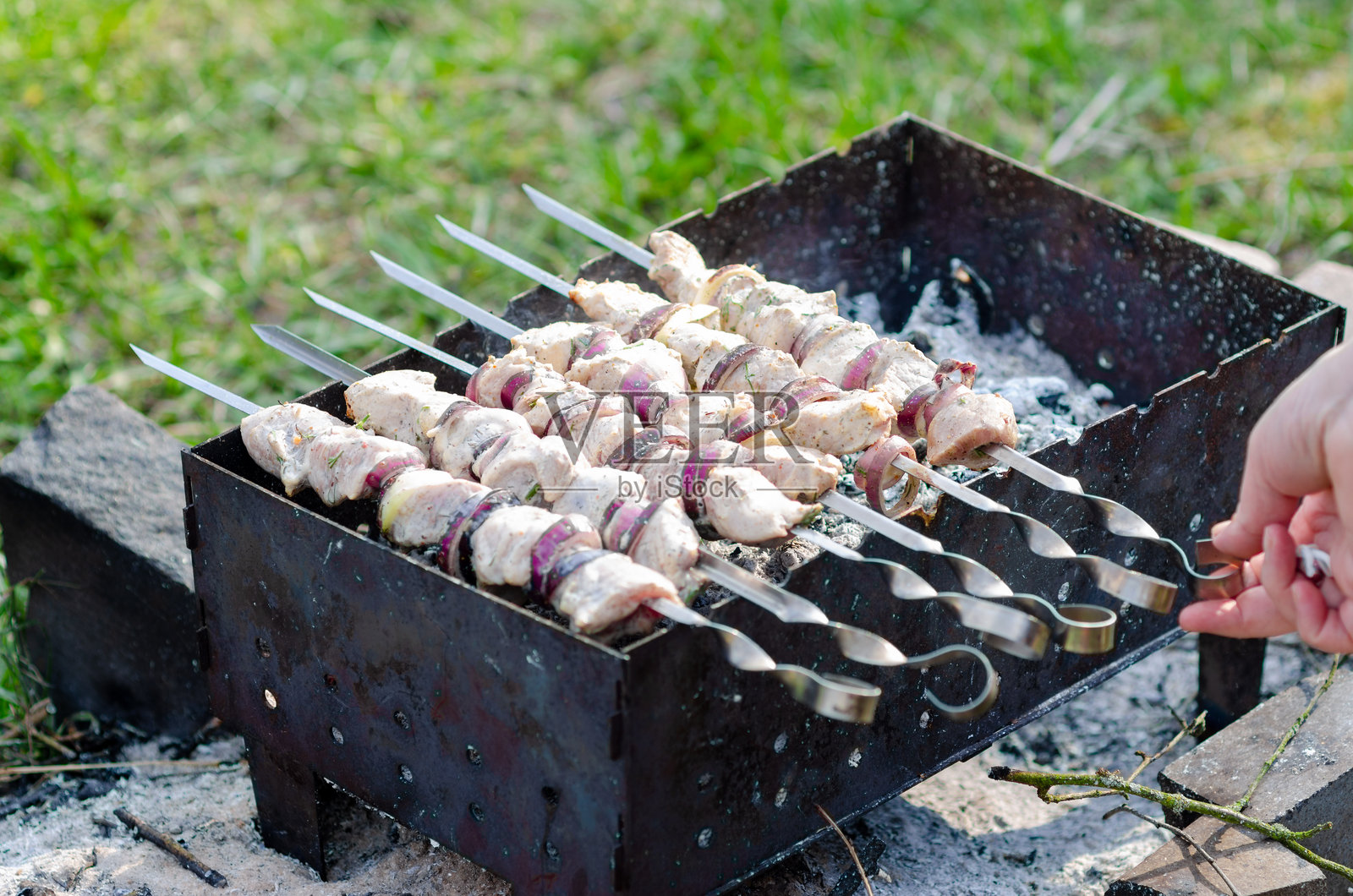 猪肉和洋葱串在金属烤架上用木炭烤的特写图片。照片摄影图片
