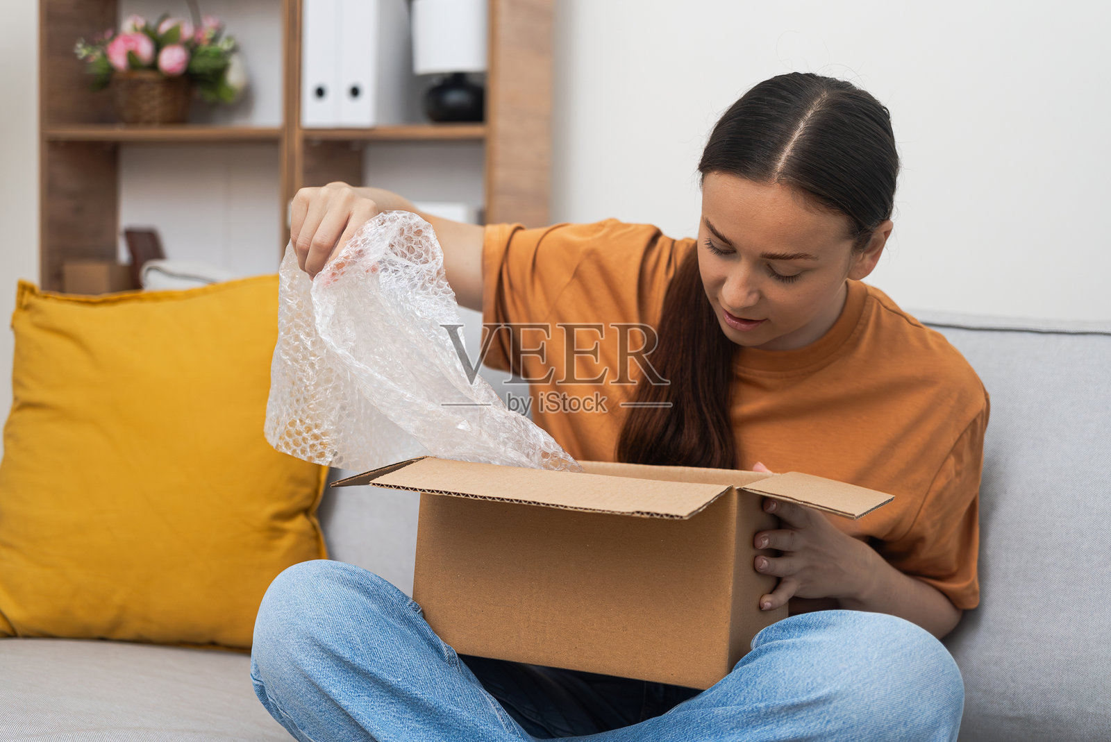 沙发上的女人检查着她的包裹，用快递满足了网购的冒险。照片摄影图片