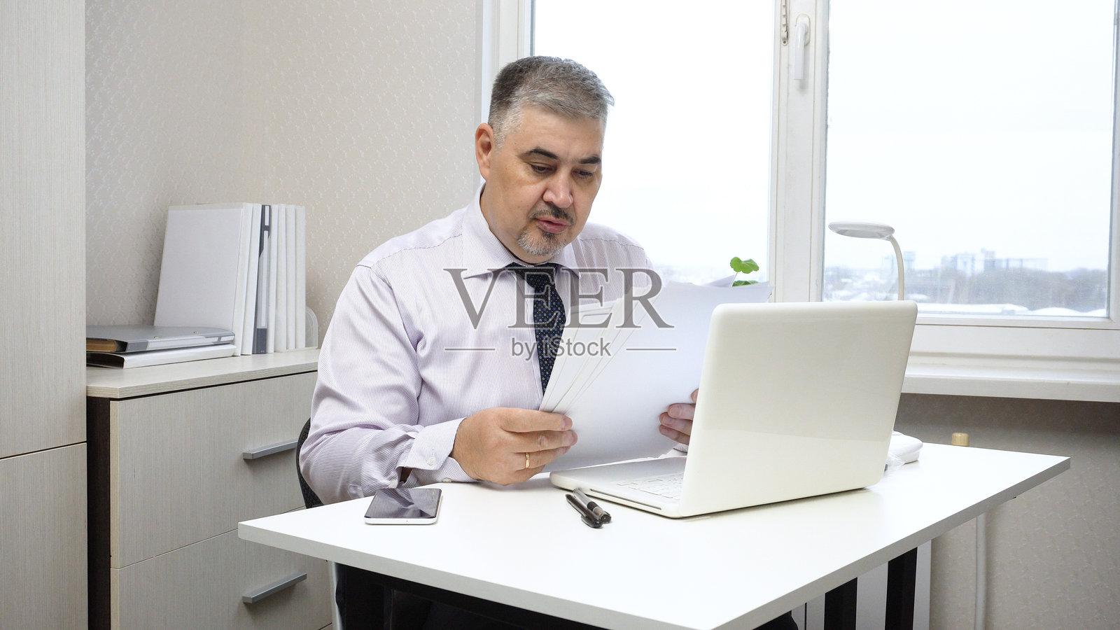 在办公室办公桌前处理文件的商人照片摄影图片