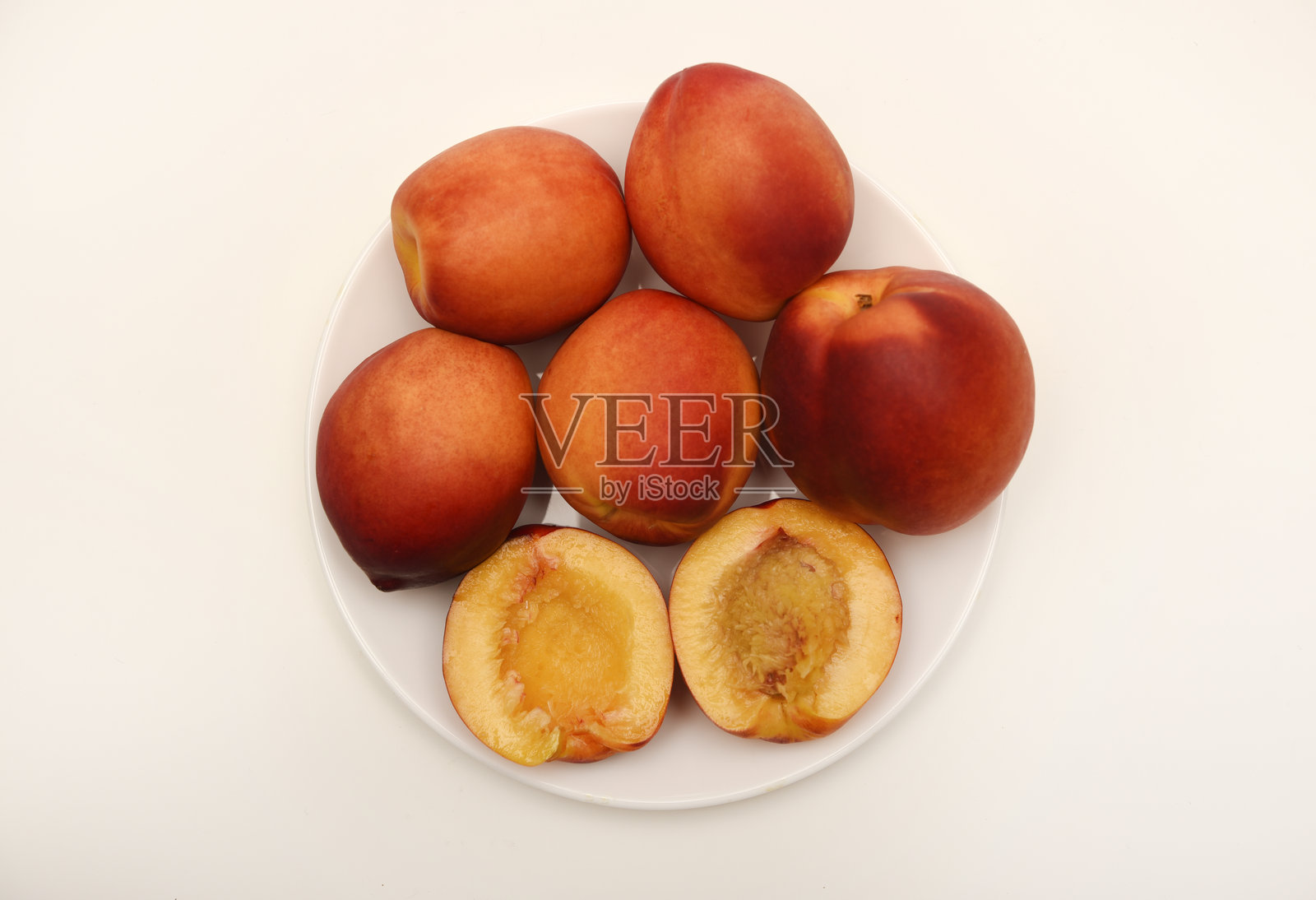 成熟的桃子放在白色的盘子里。多汁的水果。照片摄影图片