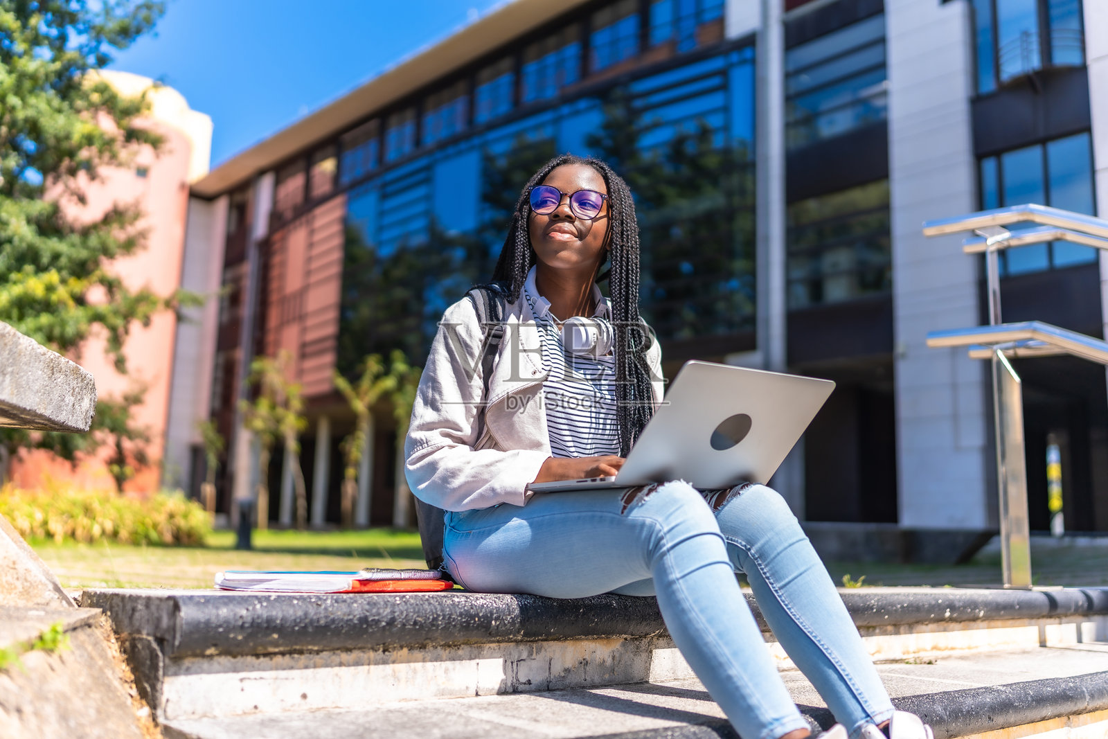 心烦意乱的非洲妇女坐在大学校园外使用笔记本电脑照片摄影图片