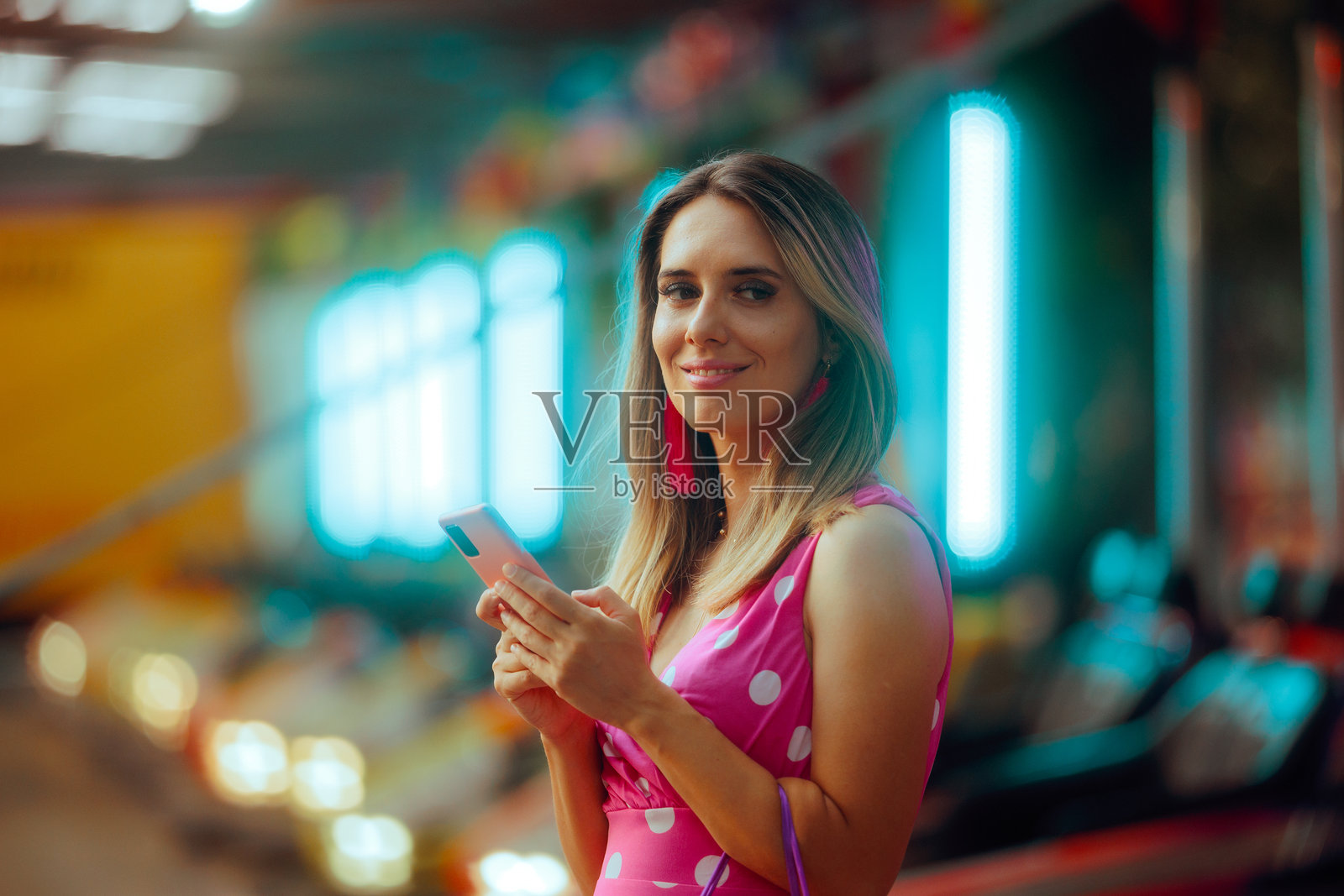 在游乐园里拿着手机微笑的女人照片摄影图片