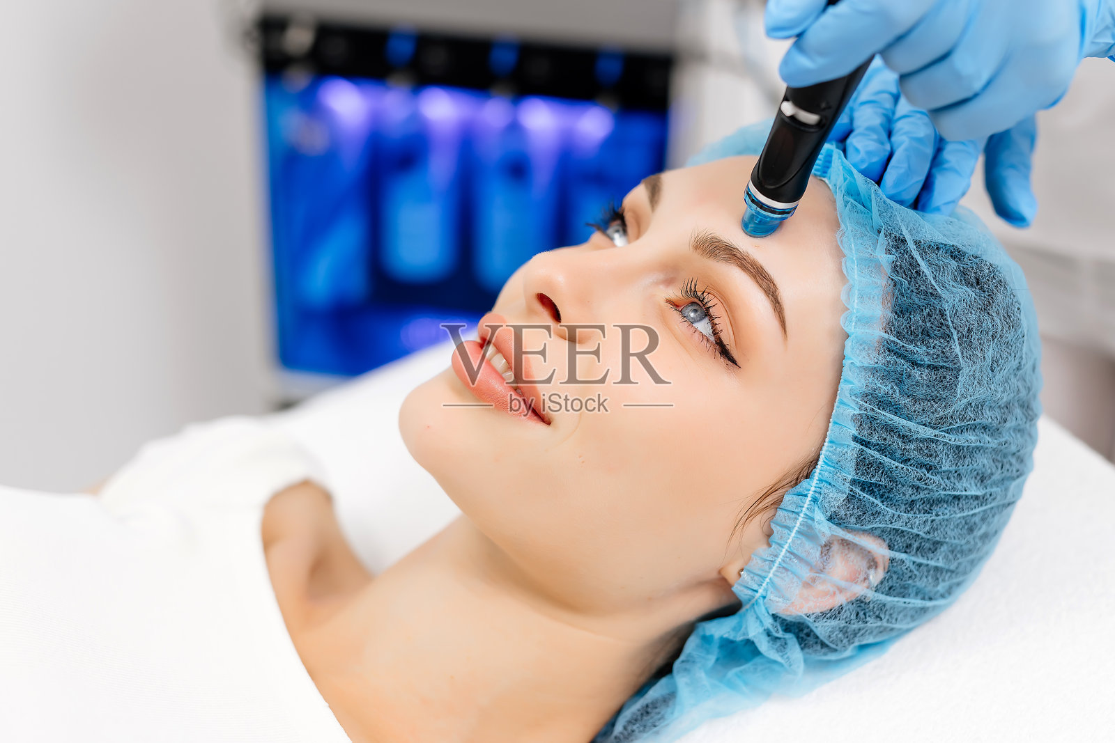 一位成熟的女性在一家高级美容院接受面部修复手术。这位美容师熟练地使用一种脱皮装置来清洁和恢复她的皮肤，展示了先进的皮肤照片摄影图片