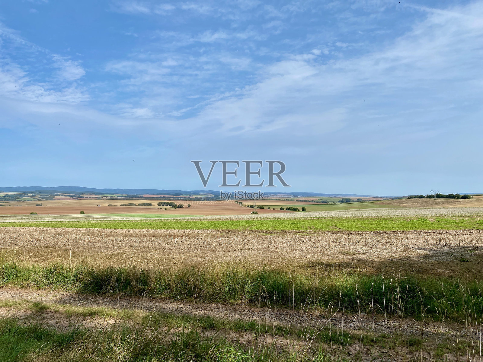 在诺德豪森附近的凯姆施泰特(Kehmstedt)徒步旅行，欣赏布莱希罗德(Bleicherode)、威珀多夫(Wipperdorf)、桑德斯豪森(Sondershausen)的废料堆、海恩莱特(Hainleite)、诺德豪森(Nordhausen)和哈茨(Harz)的拉文斯伯格(Ravensberg)，经过稻草捆和风力涡轮机照片摄影图片