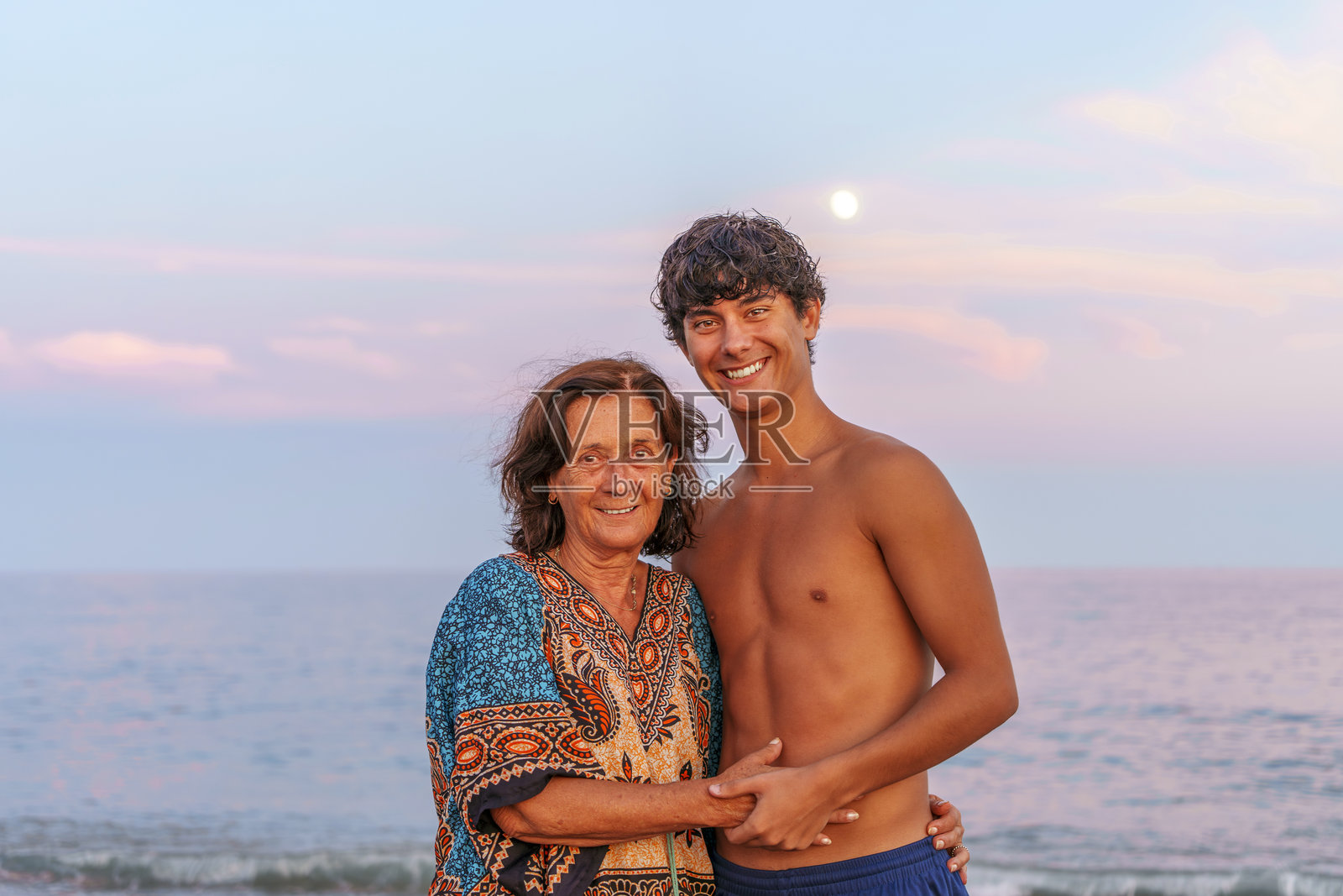 奶奶和孙子在日落的海滩上一起微笑照片摄影图片