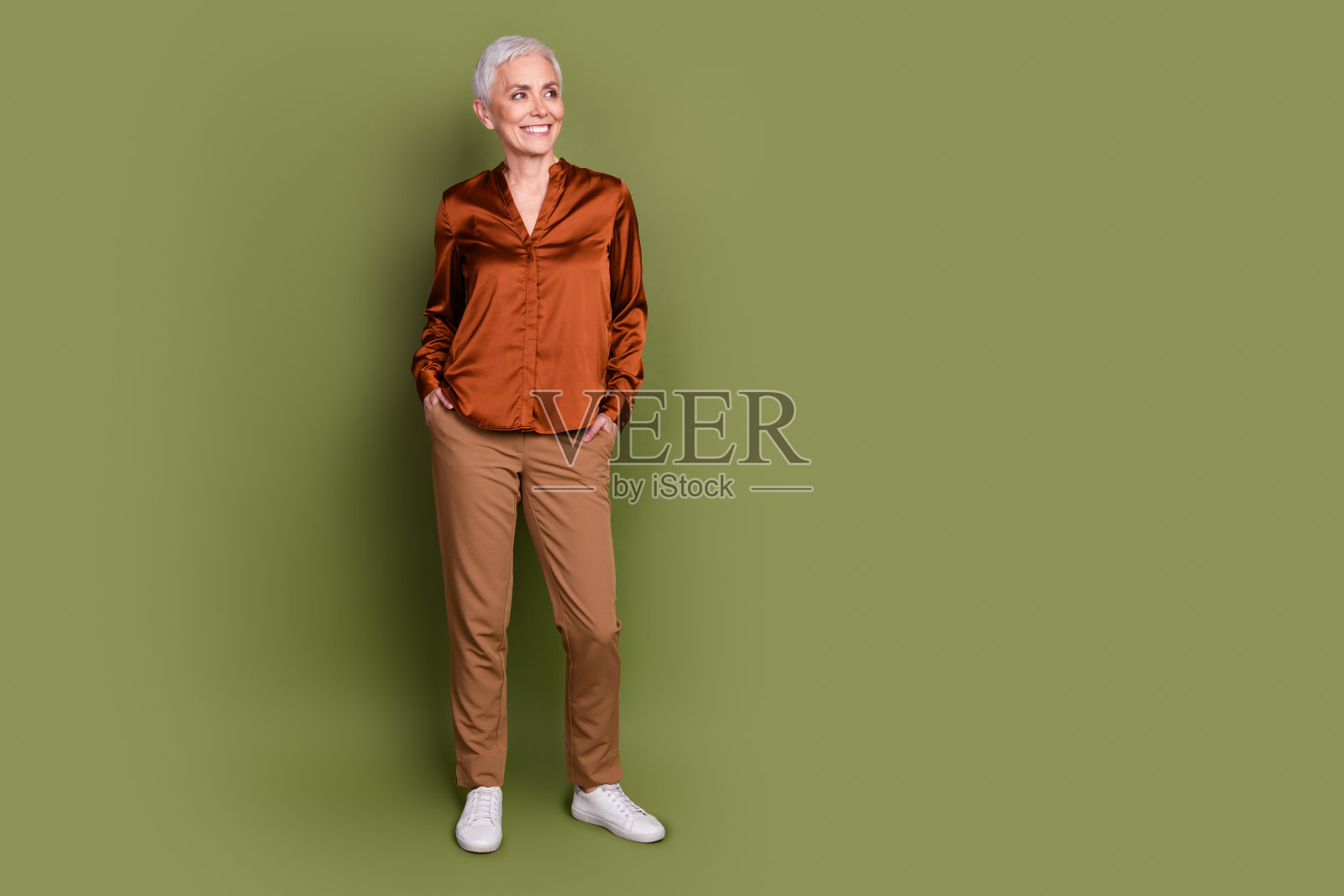 迷人的资深女性的全身照片看起来空荡荡的穿着时髦的棕色正装孤立在卡其色的背景照片摄影图片