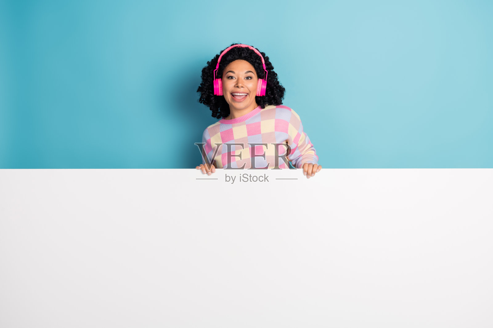 漂亮的年轻女孩的照片肖像耳机白色空白空间穿时髦的粉红色格子装孤立的蓝色背景照片摄影图片