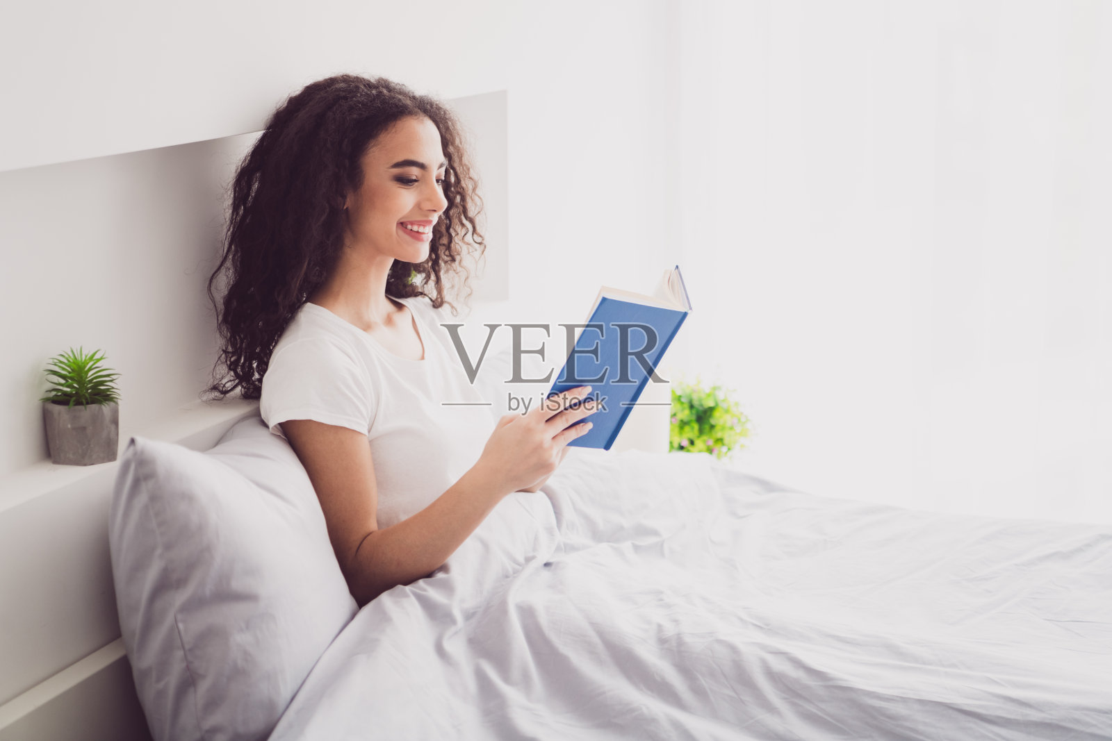 迷人的年轻女子的照片躺在床上读书早上好，唤醒家卧室光白色的内部照片摄影图片