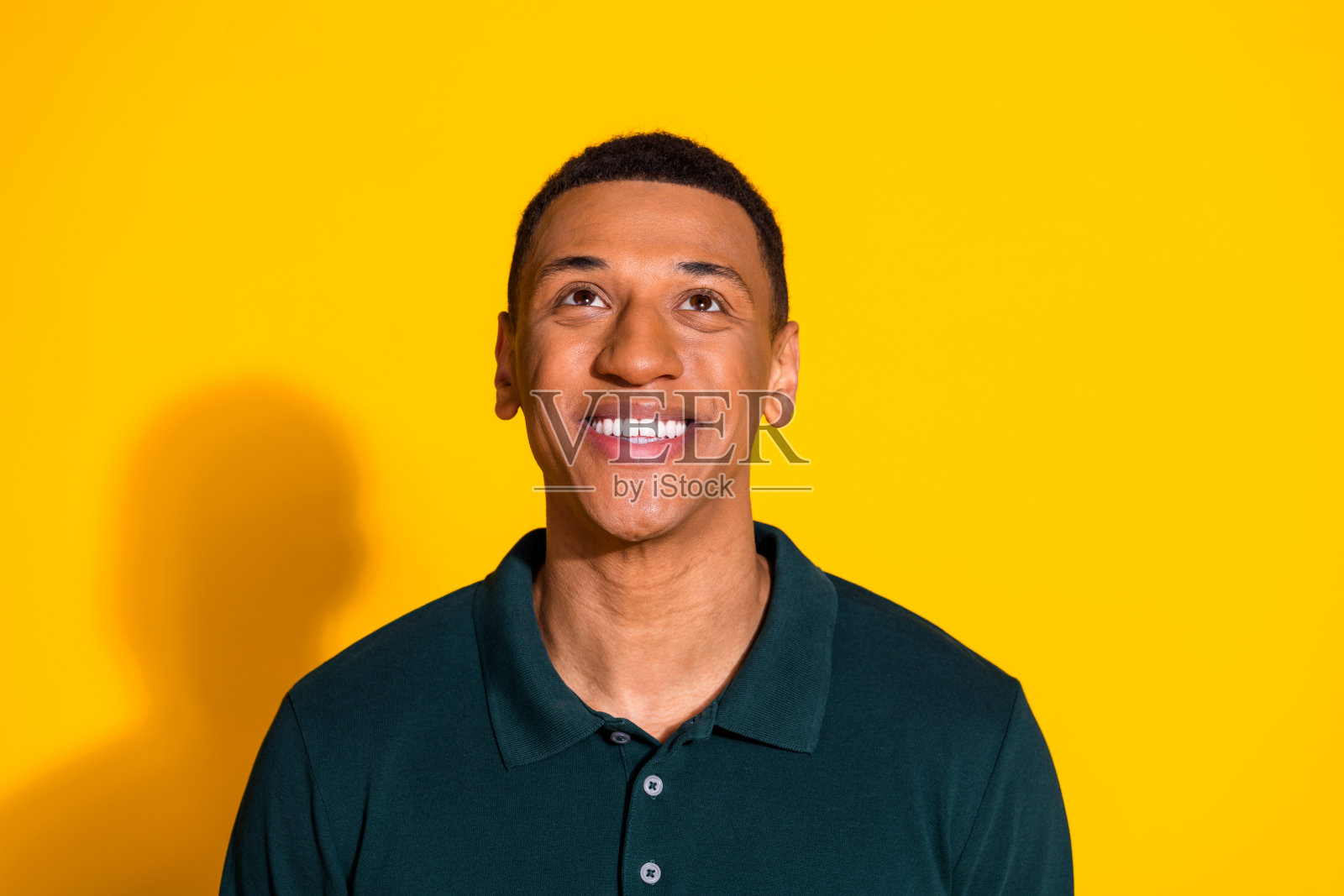 照片中漂亮的年轻人仰望空旷的空间，穿着套头衫孤立在明亮的黄色背景上照片摄影图片