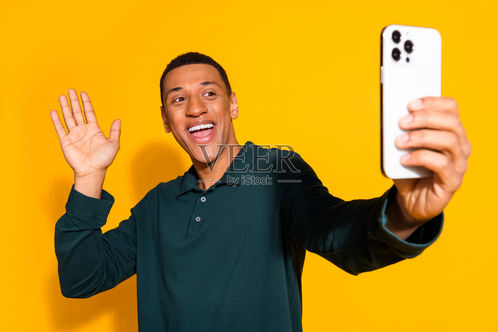 照片中英俊的年轻人的肖像自拍照片波手穿着时尚的绿色服装孤立在黄色的背景照片摄影图片