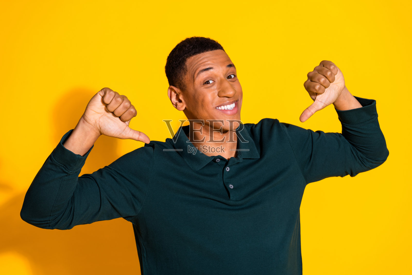 漂亮的年轻人的肖像手指自己穿套头衫孤立在充满活力的黄色背景照片摄影图片