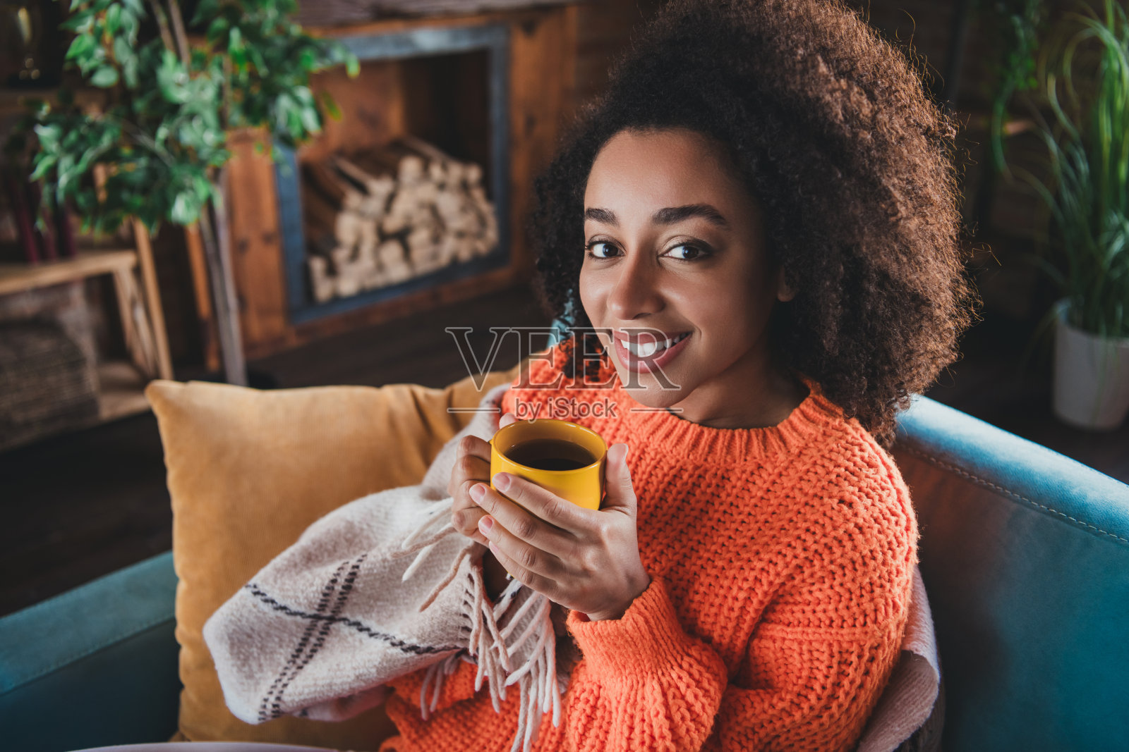 闪亮可爱的女孩穿着橙色套头衫的照片，在家里的房子公寓房间里喝茶照片摄影图片