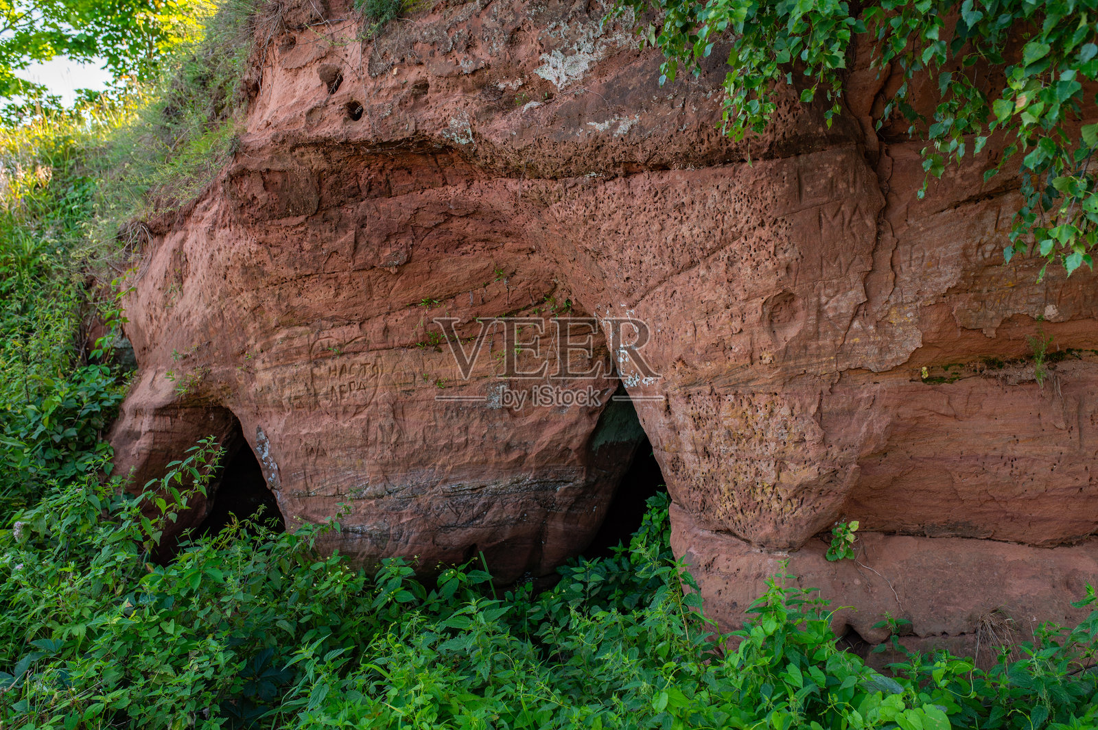 卡拉斯特兰德洞穴。爱沙尼亚东部佩浦斯湖畔美丽的砂岩悬崖。游客在悬崖上刻下文字和名字。照片摄影图片