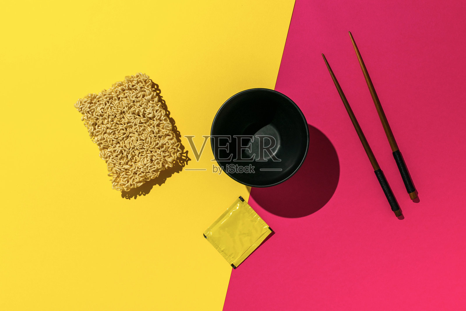 亮黄色和粉色背景上的方便面和筷子照片摄影图片