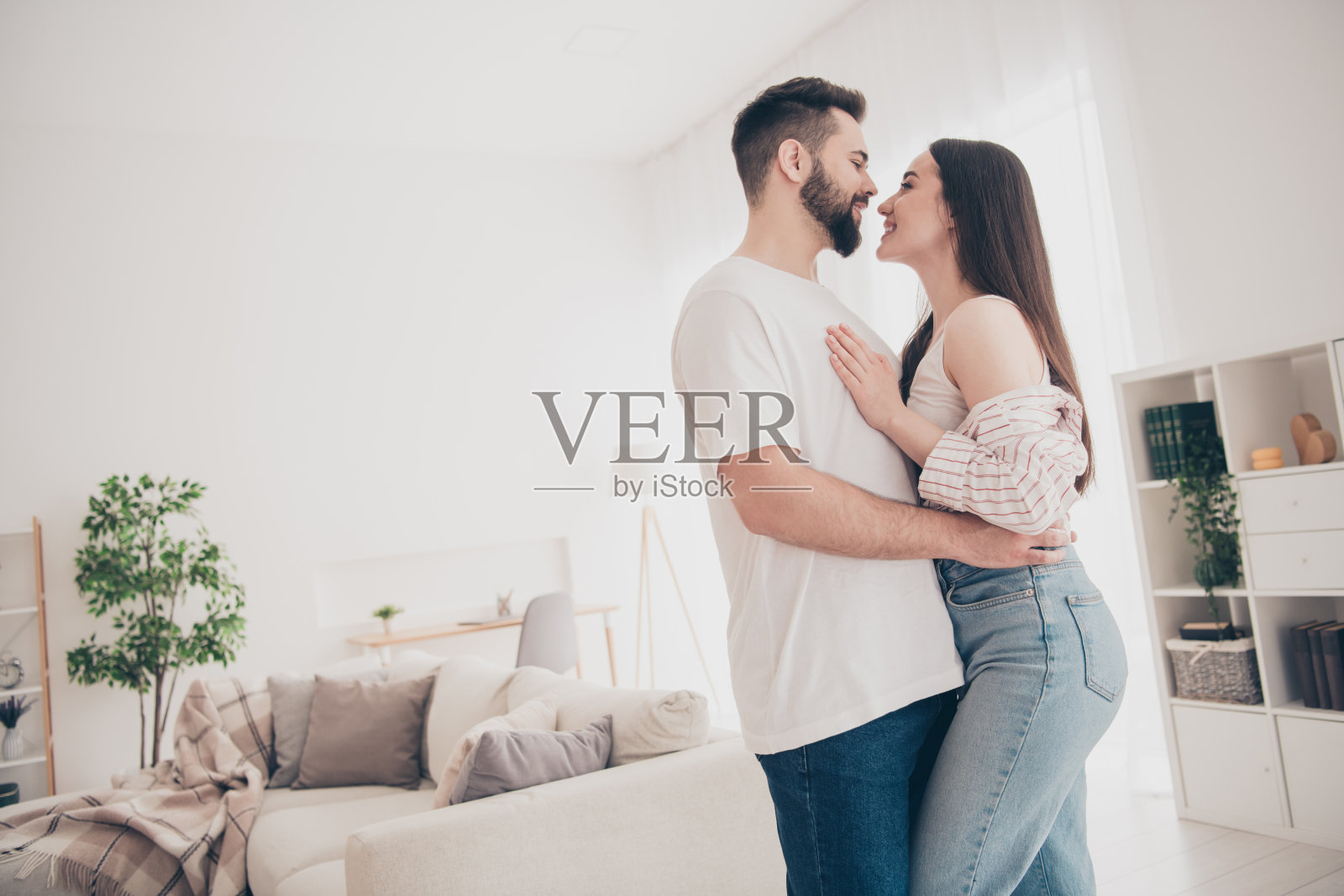 有吸引力的时髦欢快的已婚年轻夫妇的照片，他们在闲暇时间温柔地拥抱，搬家，新公寓，家，室内，室内照片摄影图片