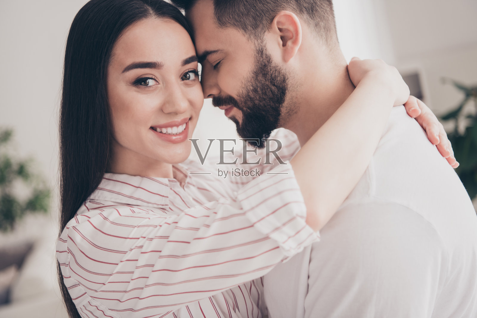 有吸引力的时髦欢快的已婚年轻夫妇的照片拥抱温柔花空闲时间搬新公寓，家室内室内照片摄影图片