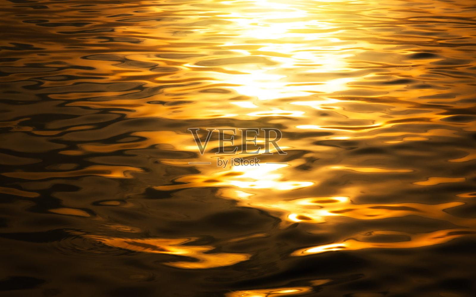 美丽的阳光反射金色的水。表面金水背景。抽象的金色纹理背景。照片摄影图片