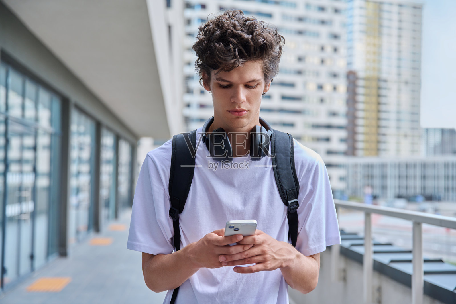 年轻人使用智能手机，现代城市街道背景照片摄影图片