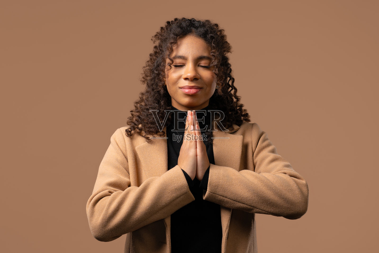 虔诚的少女在祈祷，读祈祷文，米色背景。希望，祝愿，感恩照片摄影图片