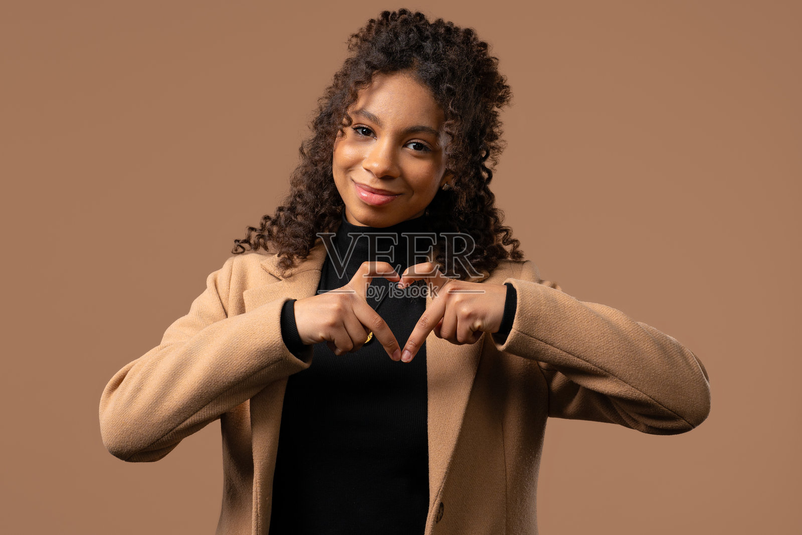 十几岁的女孩显示出心形的迹象。肯定是米色女士。爱。照片摄影图片