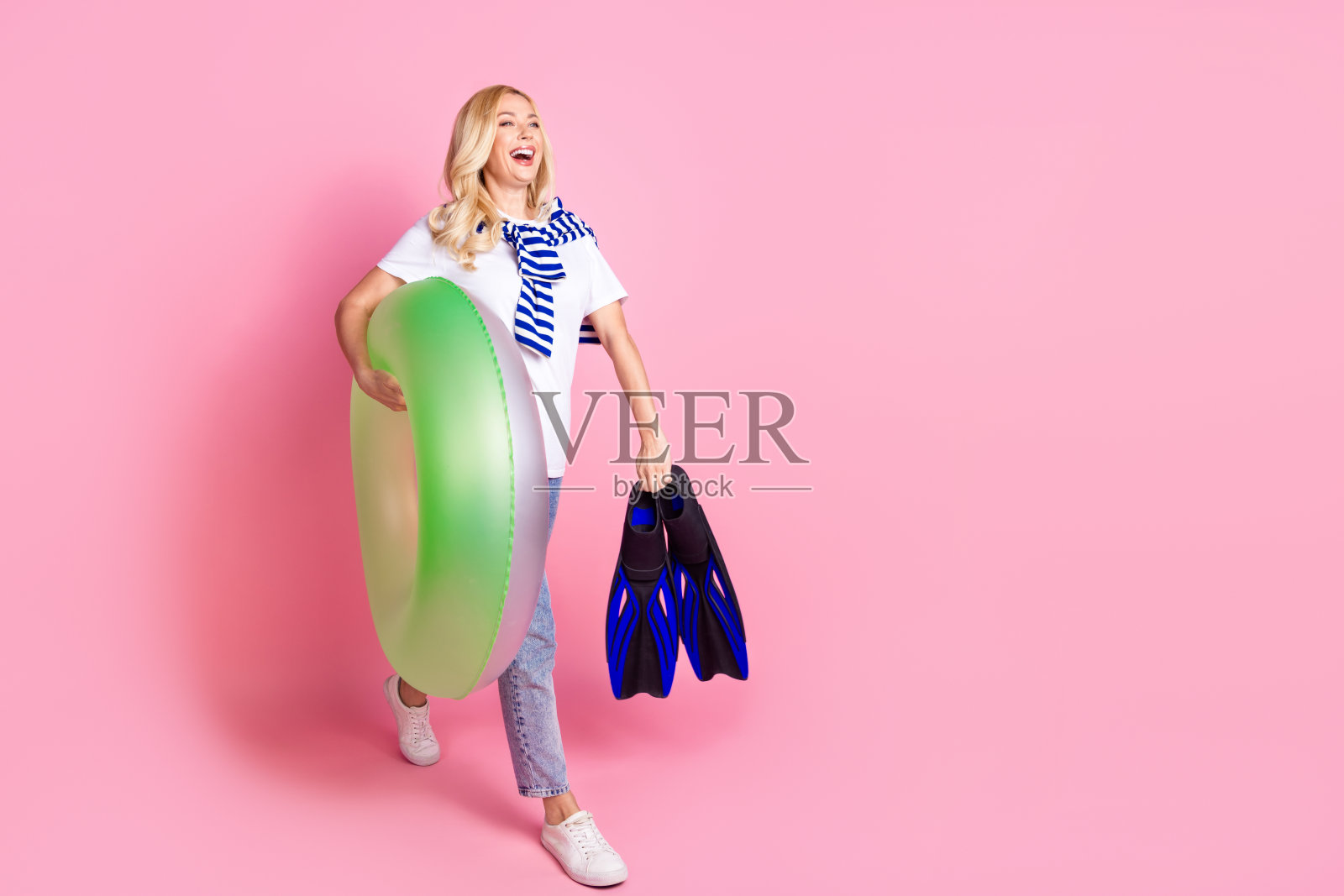 可爱的女士的全身照片充气环鳍走路看空空间穿着白色的衣服孤立在粉红色的背景照片摄影图片