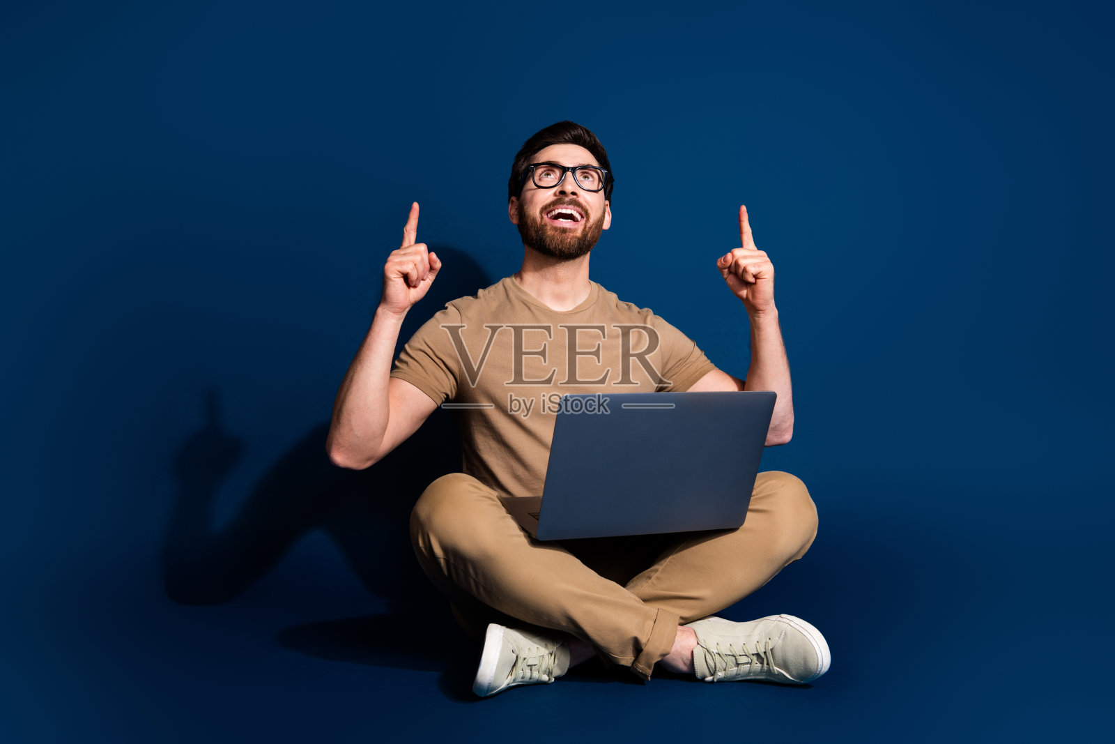 成熟年龄的营销人员黑发男子坐在笔记本电脑直接手指以上的营销策略孤立的深蓝色背景的照片照片摄影图片