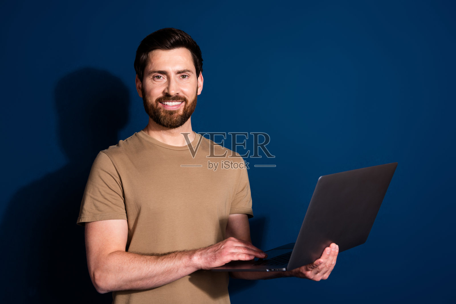 成熟年龄的照片高级it专家程序员黑发男子与上网本在网上工作孤立的深蓝色背景照片摄影图片