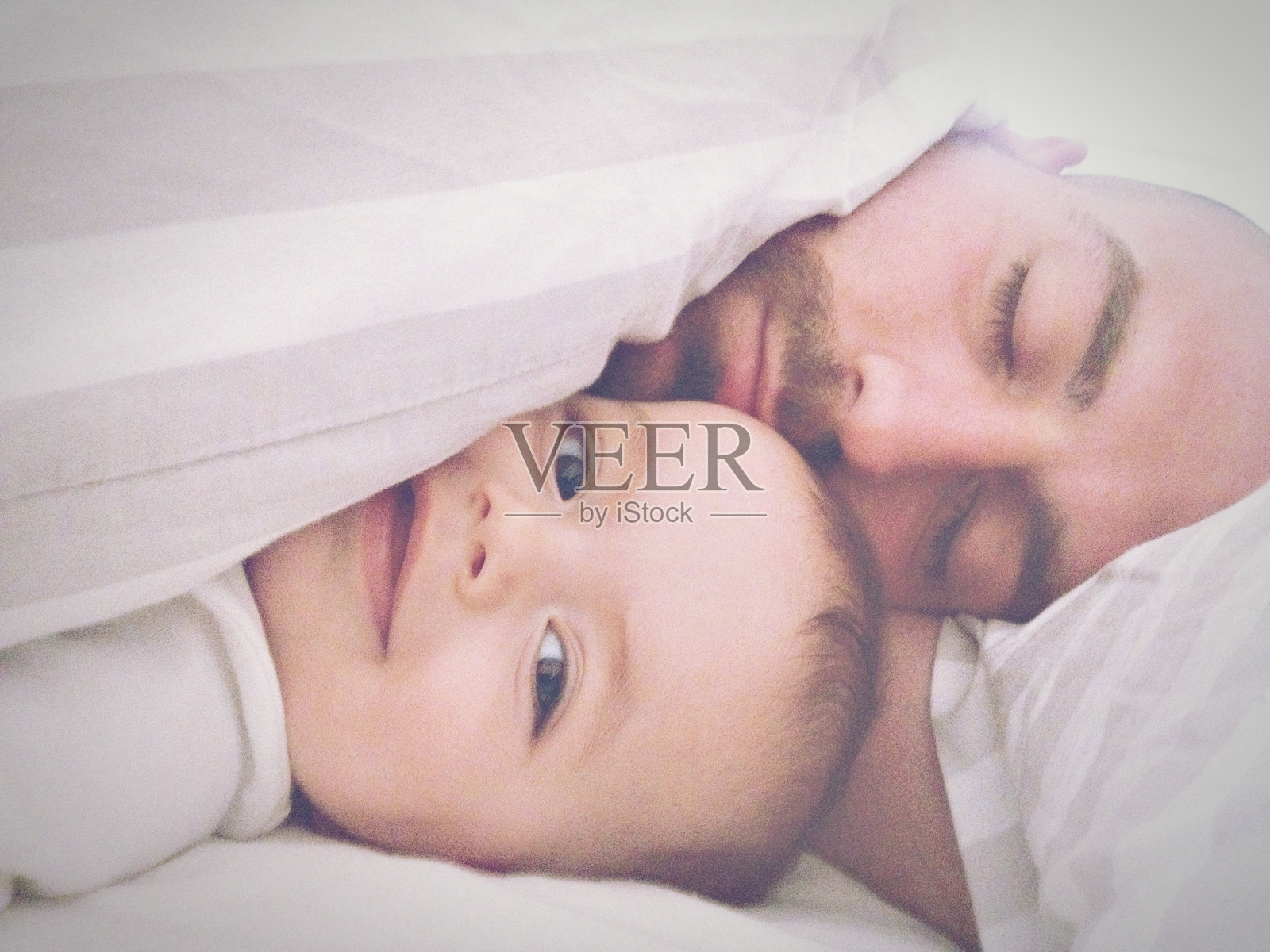 父子躺在家里床上的特写照片摄影图片