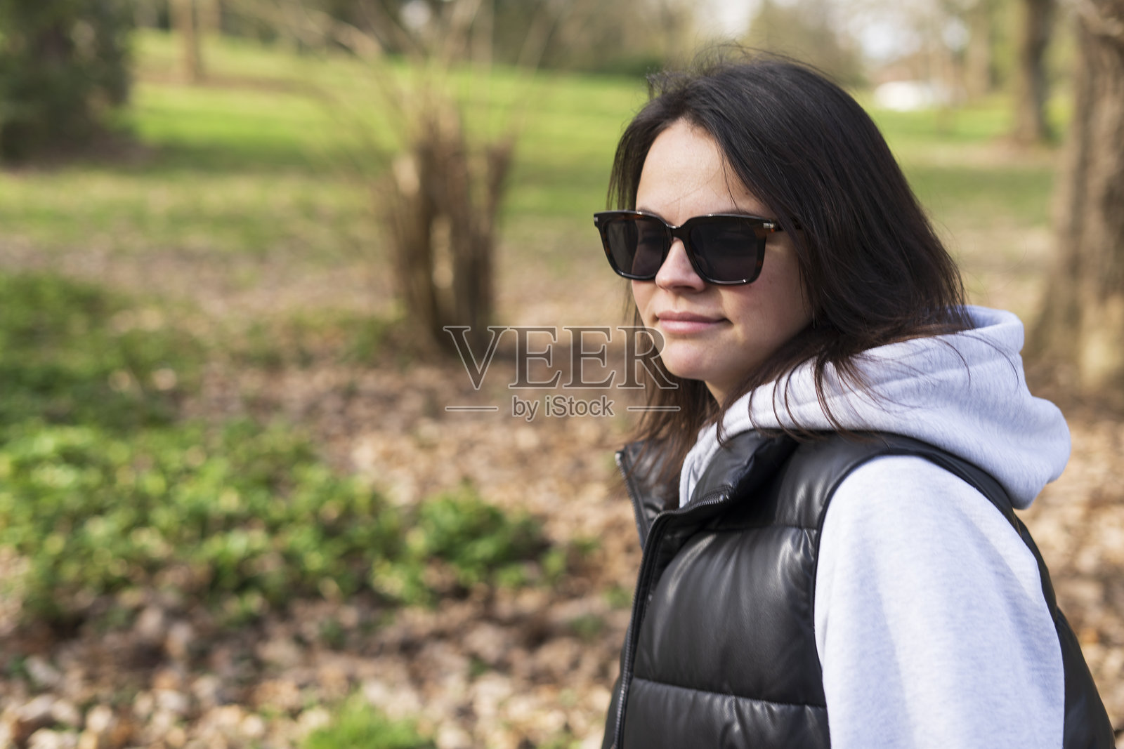 一个戴着墨镜的黑发中年女孩在秋天的公园里照片摄影图片
