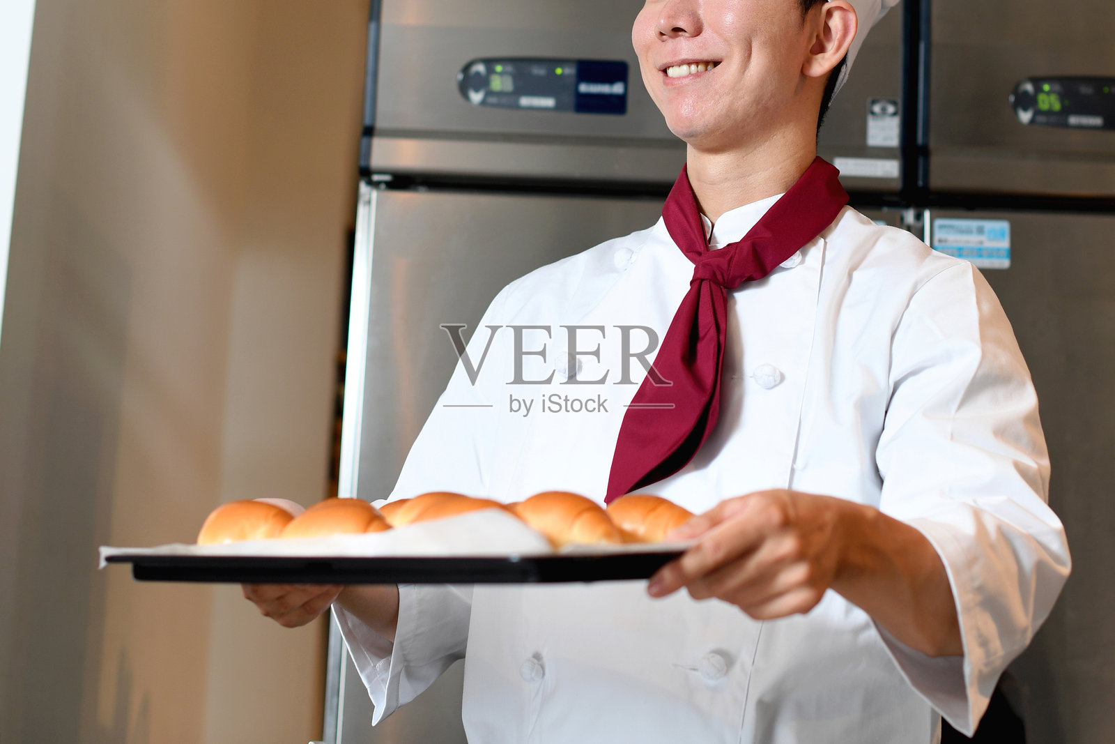 穿着厨师服的年轻亚洲男子在厨房做面包照片摄影图片