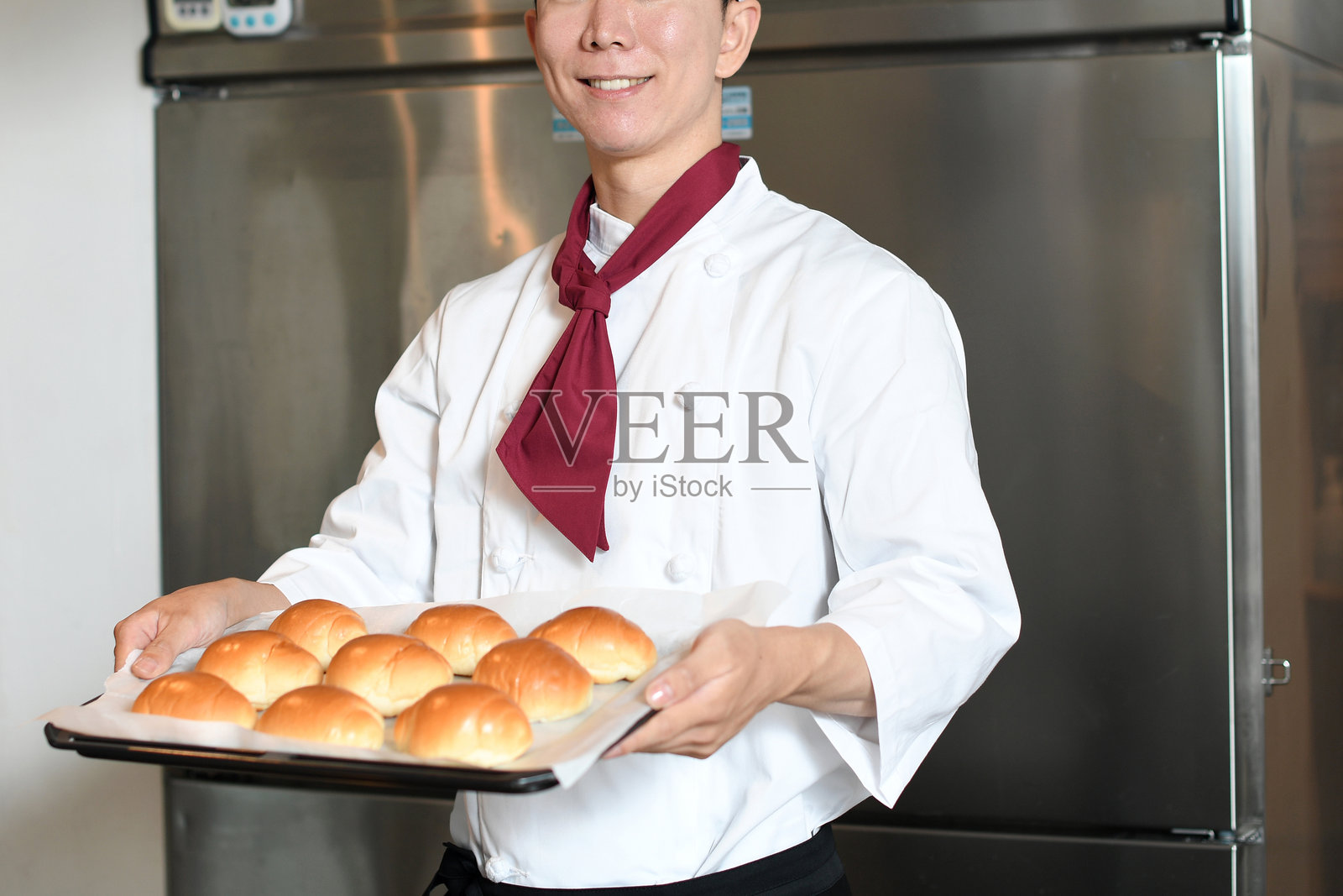 穿着厨师服的年轻亚洲男子在厨房做面包照片摄影图片