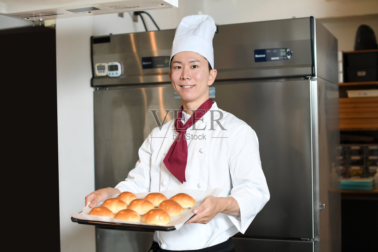 穿着厨师服的年轻亚洲男子在厨房做面包照片摄影图片