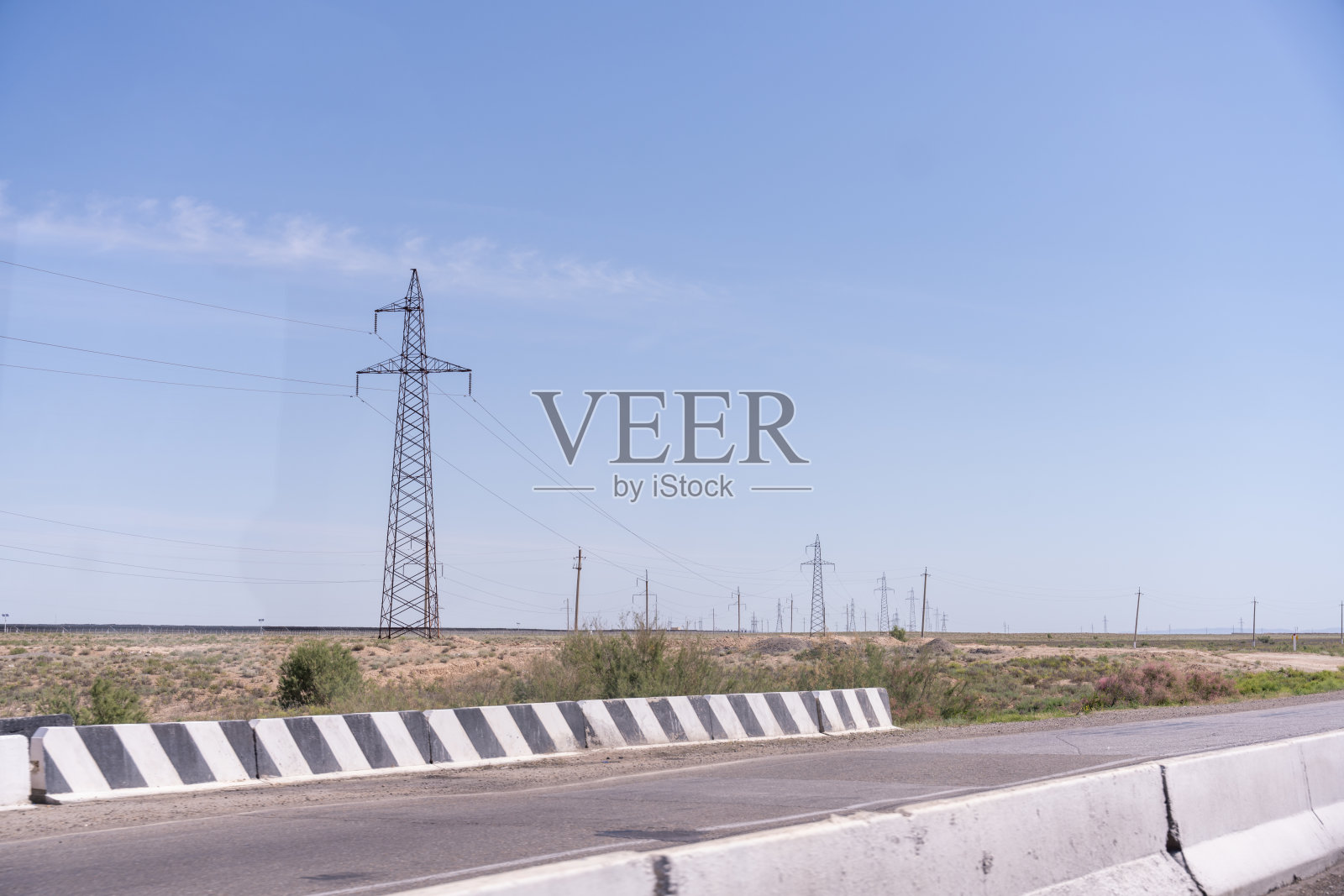 电力线塔在田野的中央。天空晴朗而湛蓝。电力线塔很高，有很多电线照片摄影图片